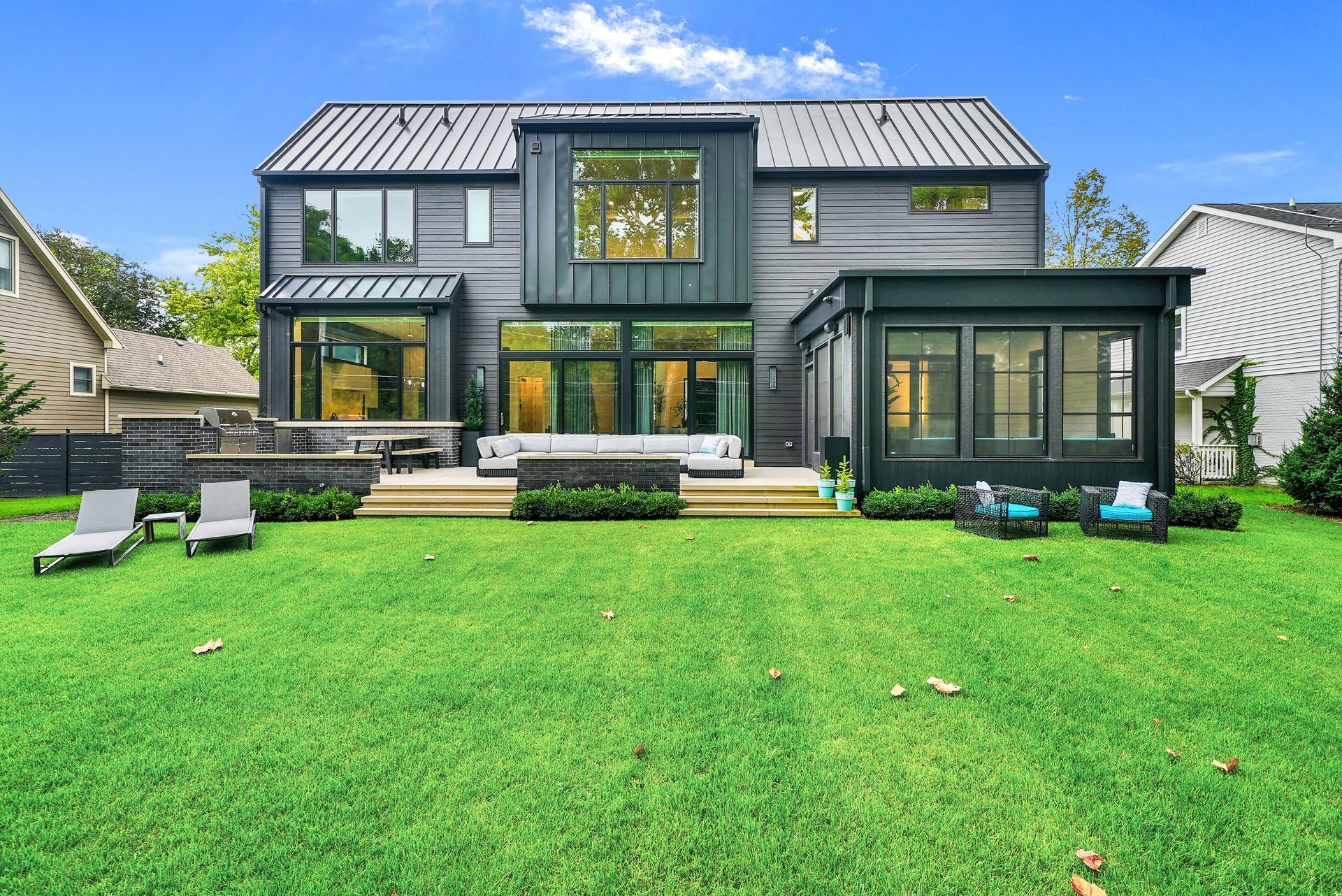 Modern two-story gray house with large windows and a bright green lawn in front