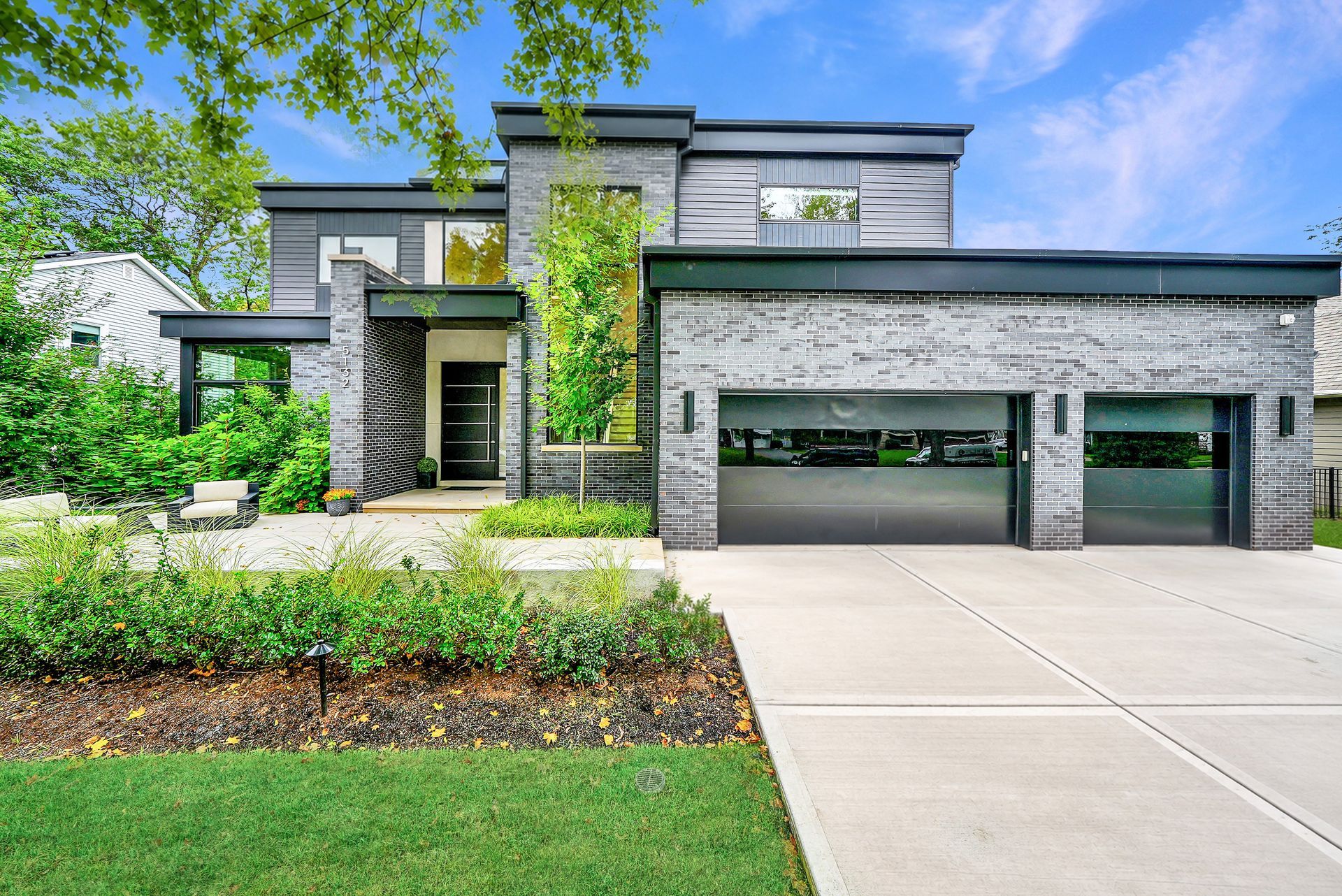 Modern two-story house with stone facade, large garage, and landscaped front yard