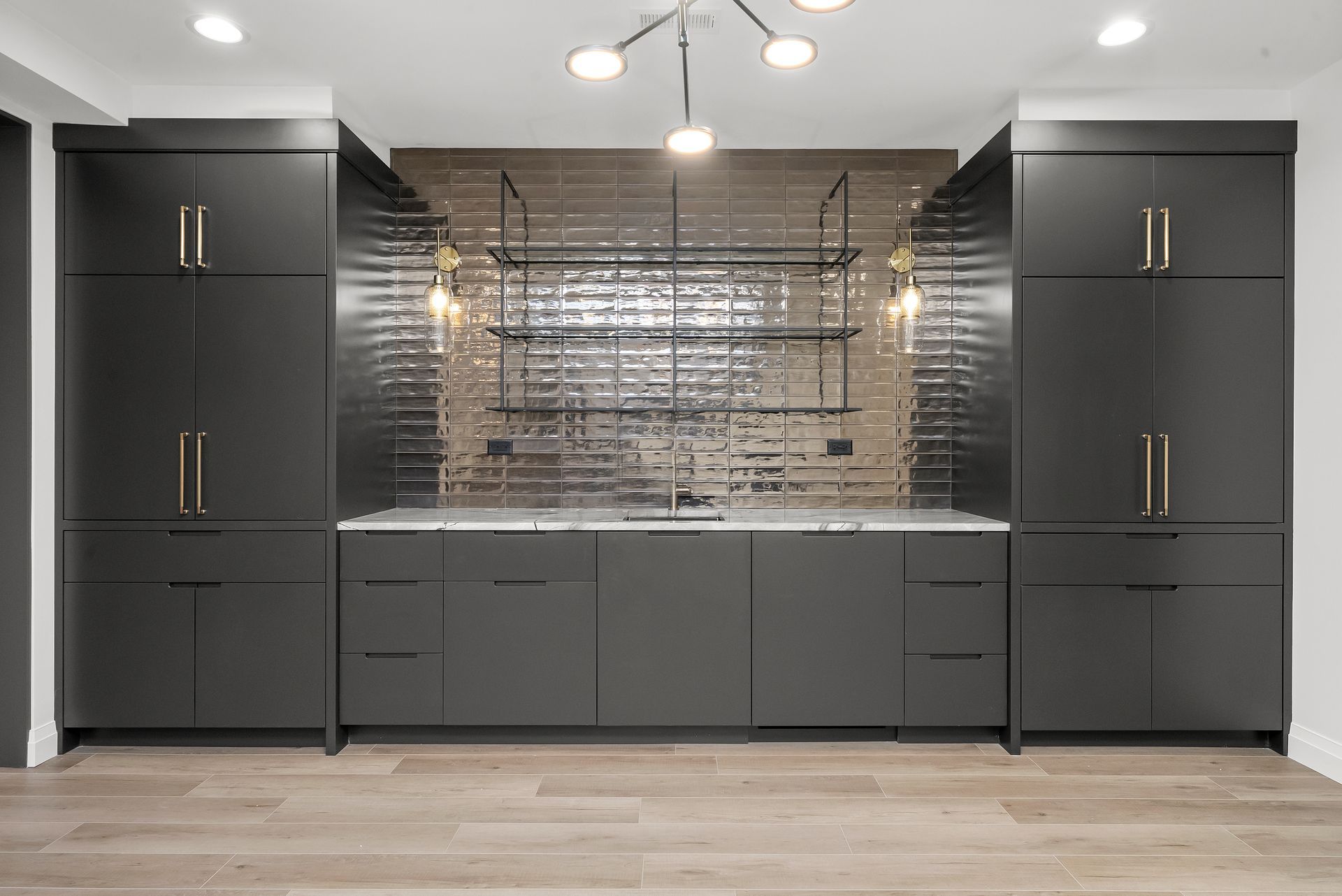 Modern gray kitchen with dark cabinets, metallic backsplash, and wood floor