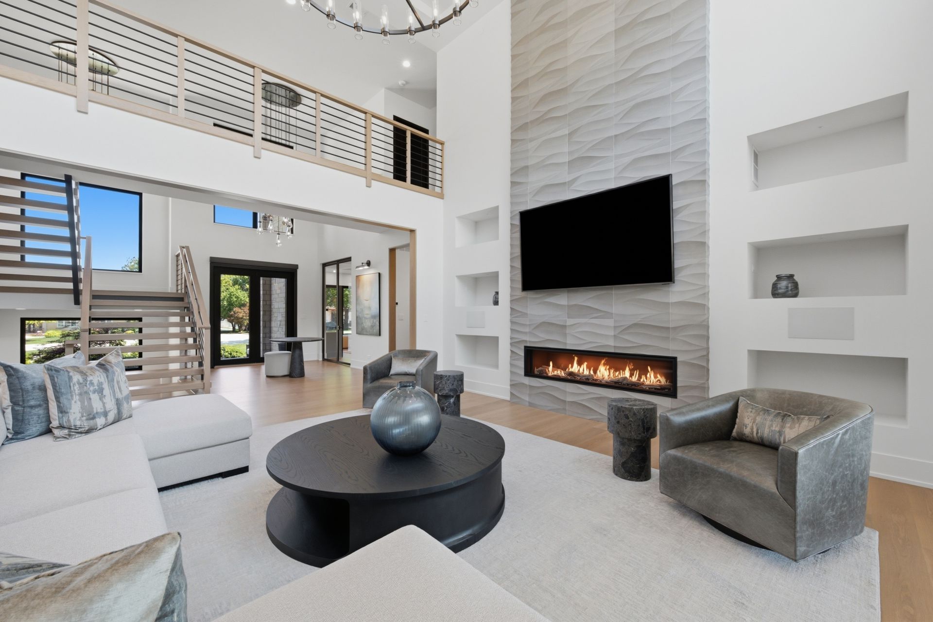 Modern living room with white walls, fireplace, TV, gray seating, and a round black coffee table