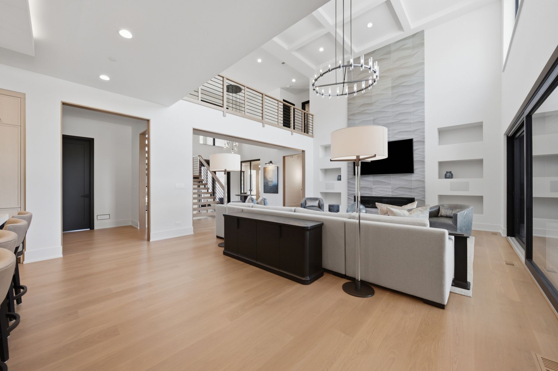 Modern open-concept living room with white walls, wood floors, gray sofas, and a fireplace