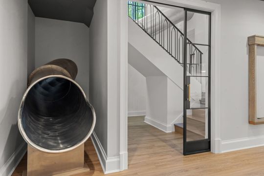 Indoor home with a spiral slide beside a staircase and light wood floors