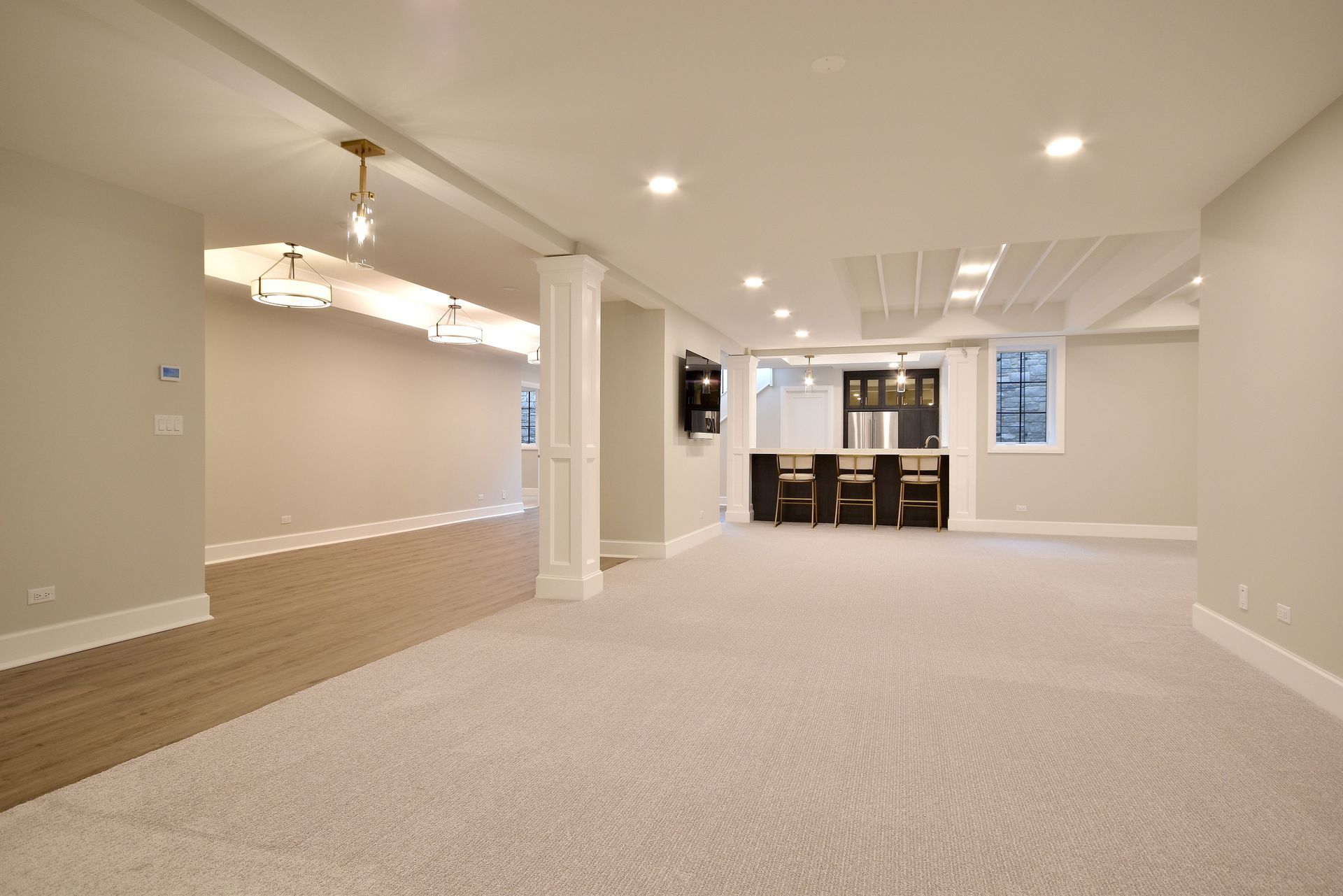Spacious finished basement with beige carpet, recessed lights, and a dining area in the back.