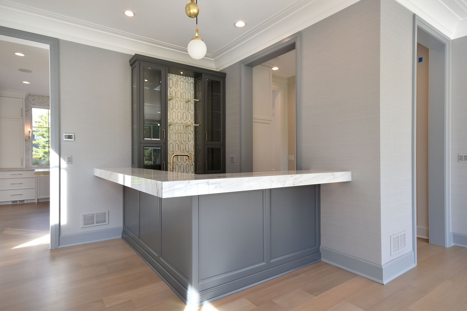 Modern gray kitchen with a large white island and pendant lights in a bright open room