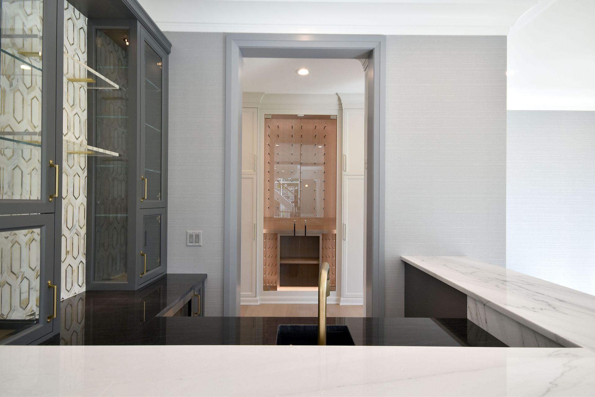 Modern kitchen with dark cabinets, white island, and a view through a doorway into a tiled room