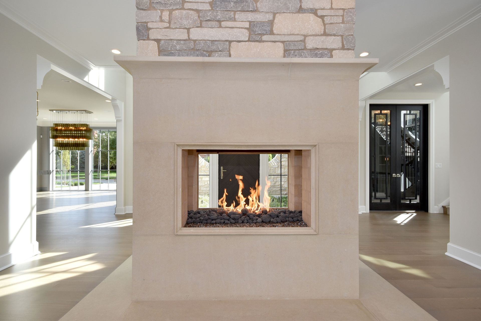 Modern living room with a central stone fireplace and open doorways on both sides