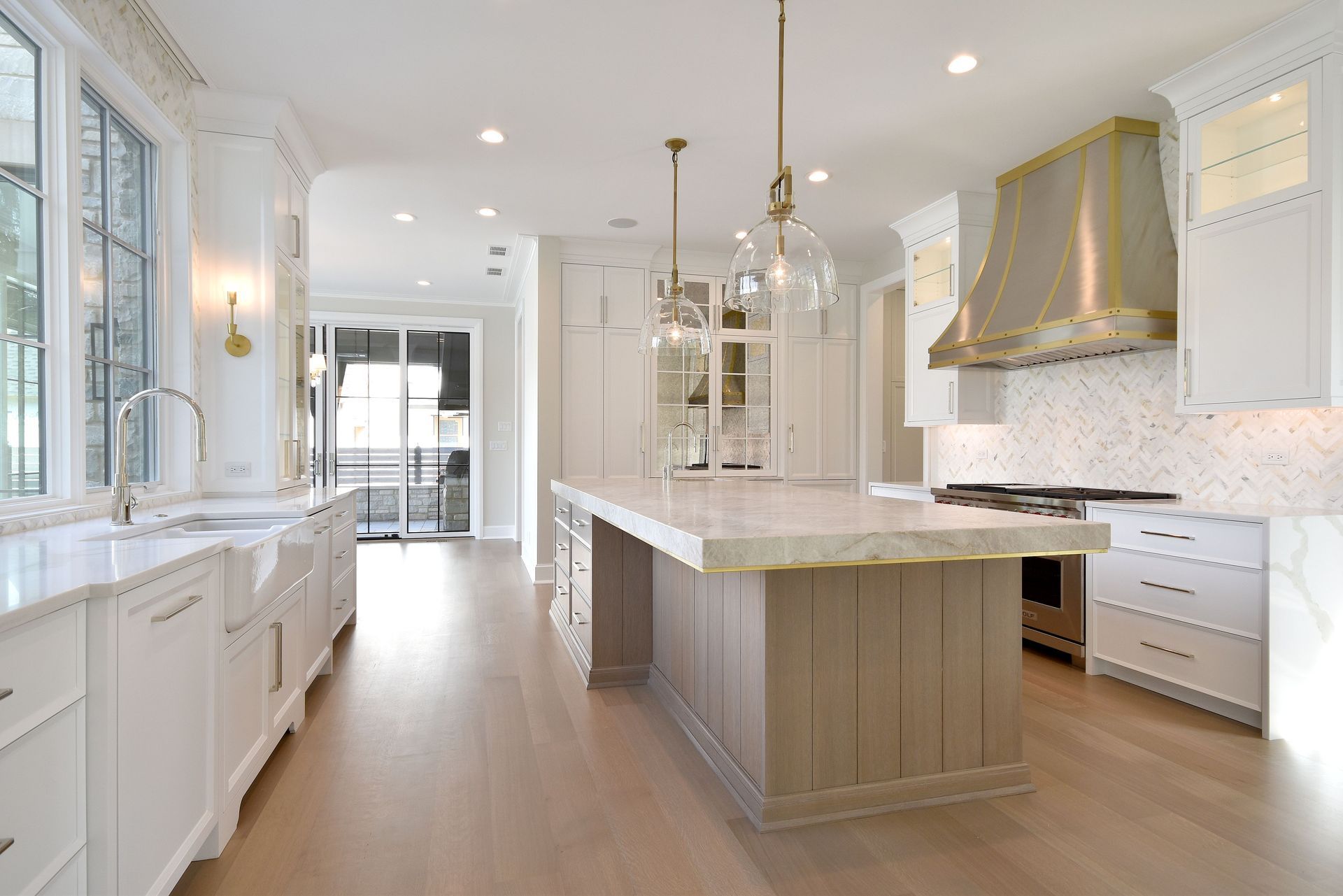 Bright modern white kitchen with large island, stainless range hood, and wood floors