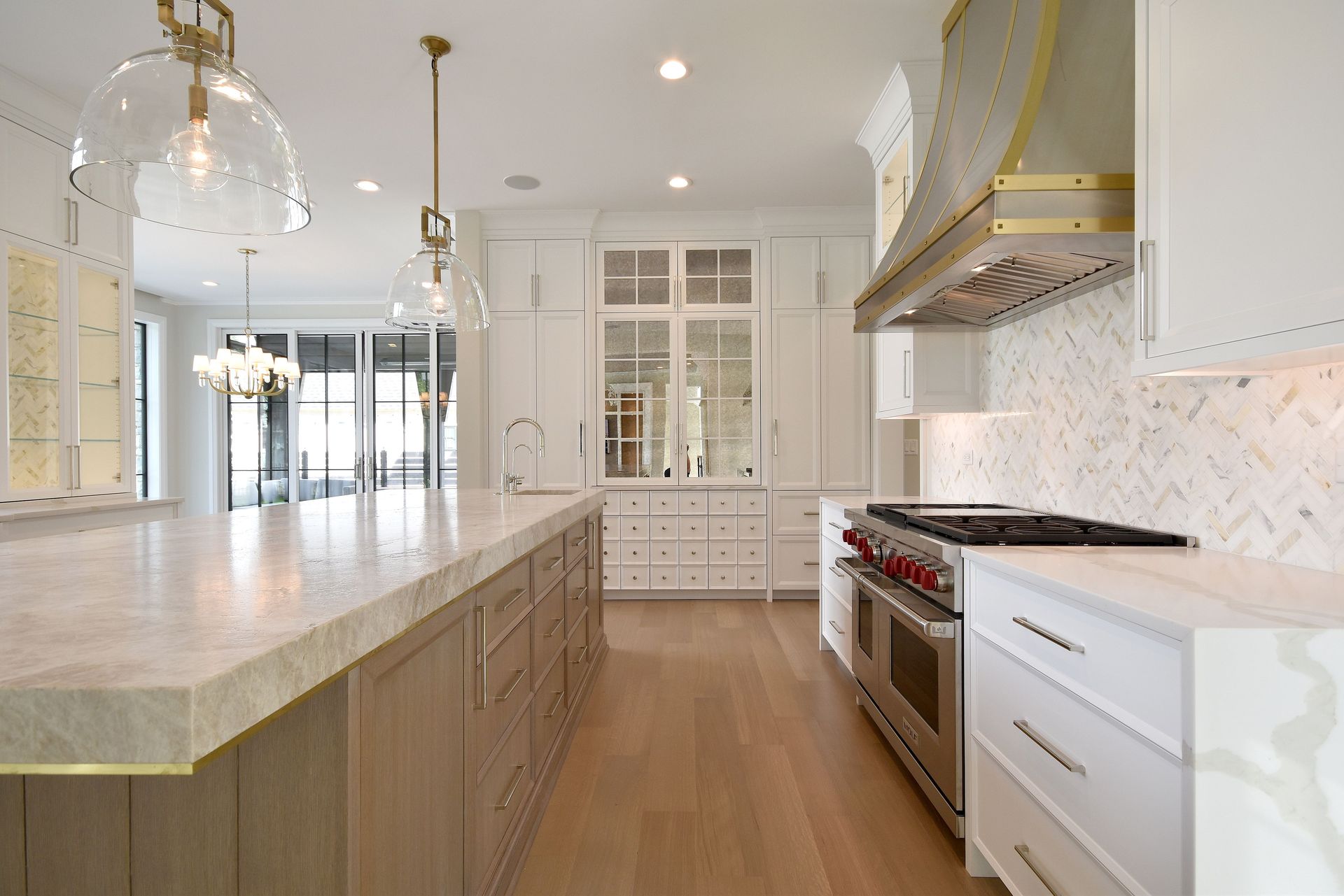 Bright modern kitchen with large island, white cabinets, stainless steel appliances, and brass pendant lights