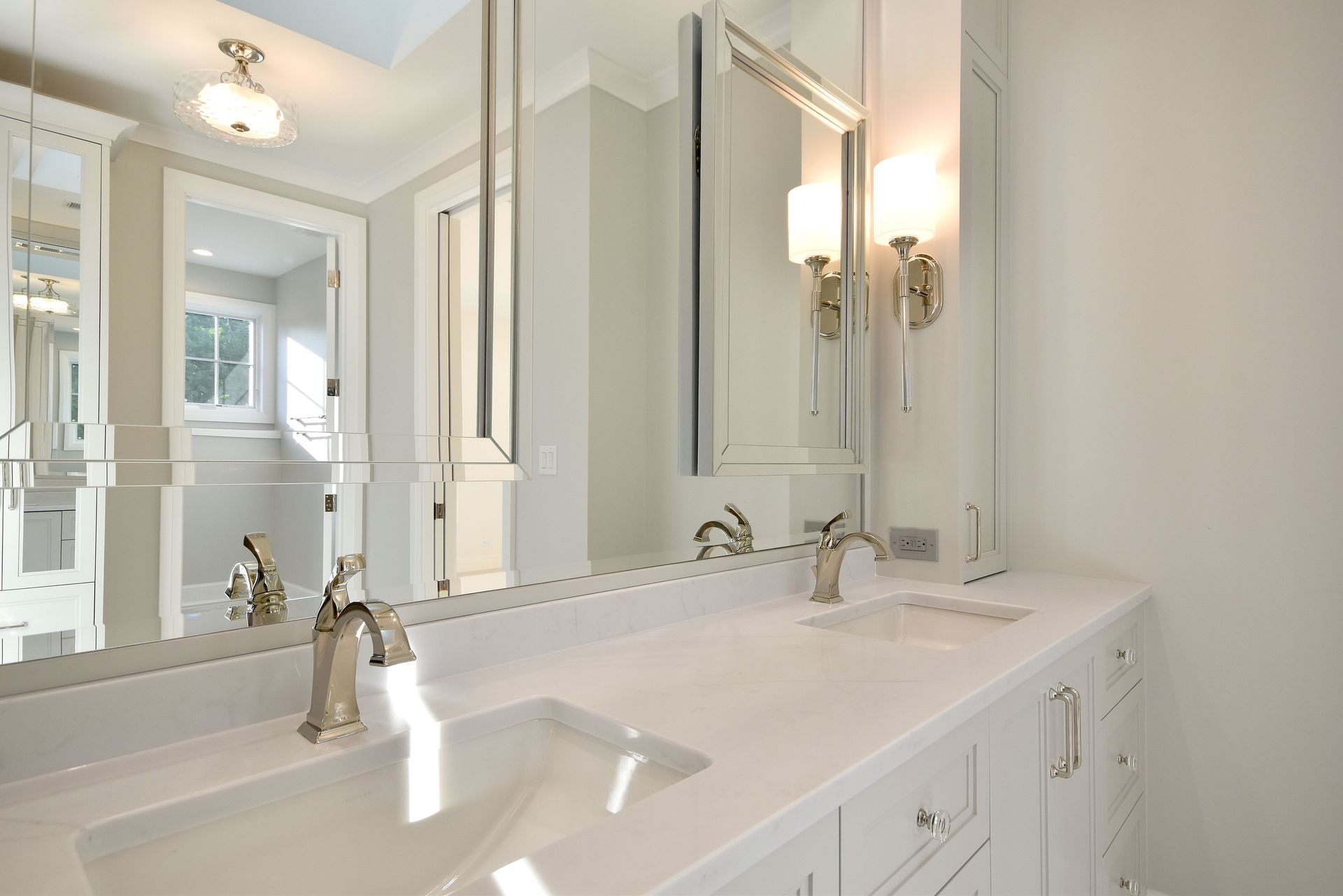 Bright white bathroom vanity with double sinks, large mirror, and wall sconces in a clean, elegant interior