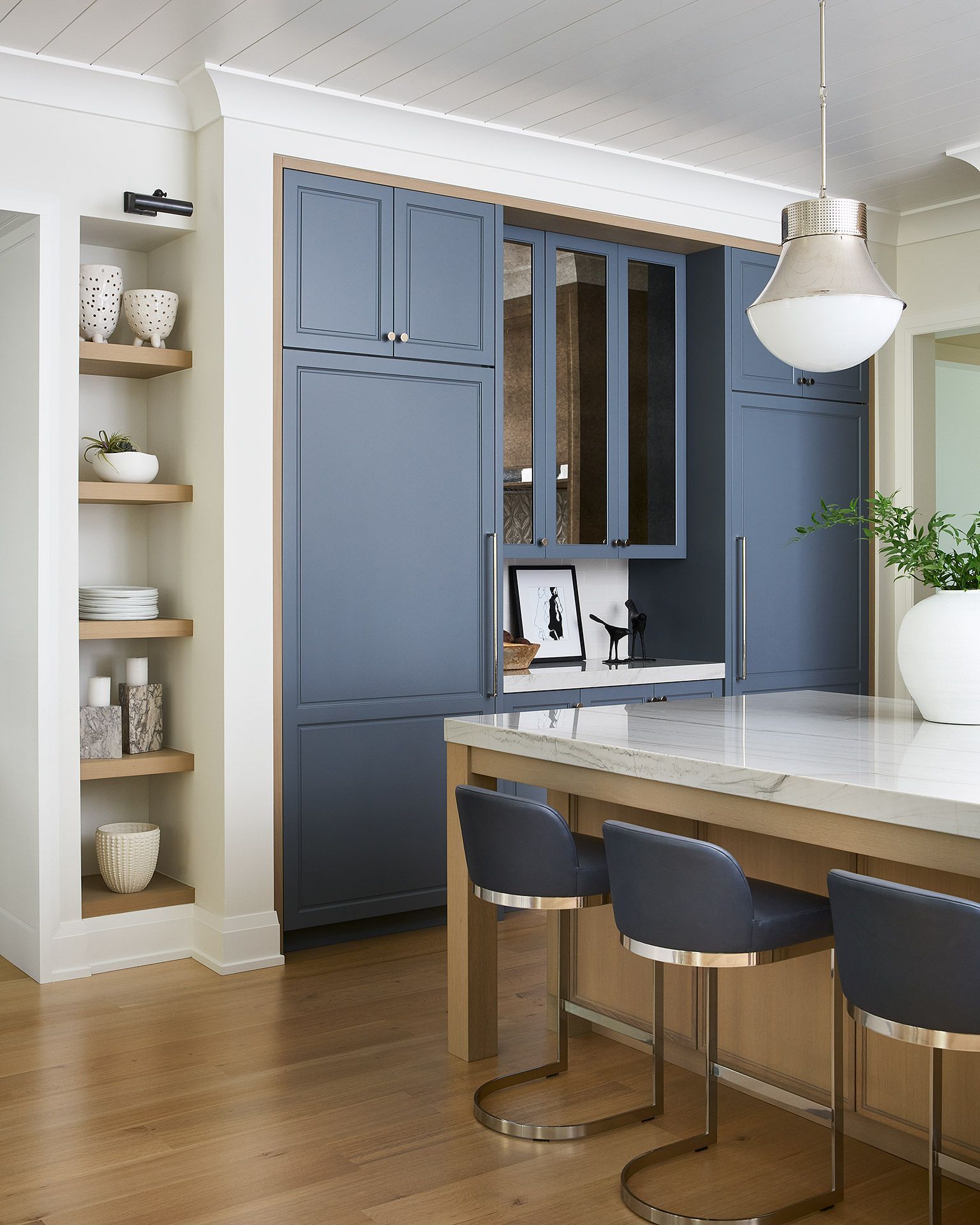 Modern kitchen with blue cabinets, white island, and two stools