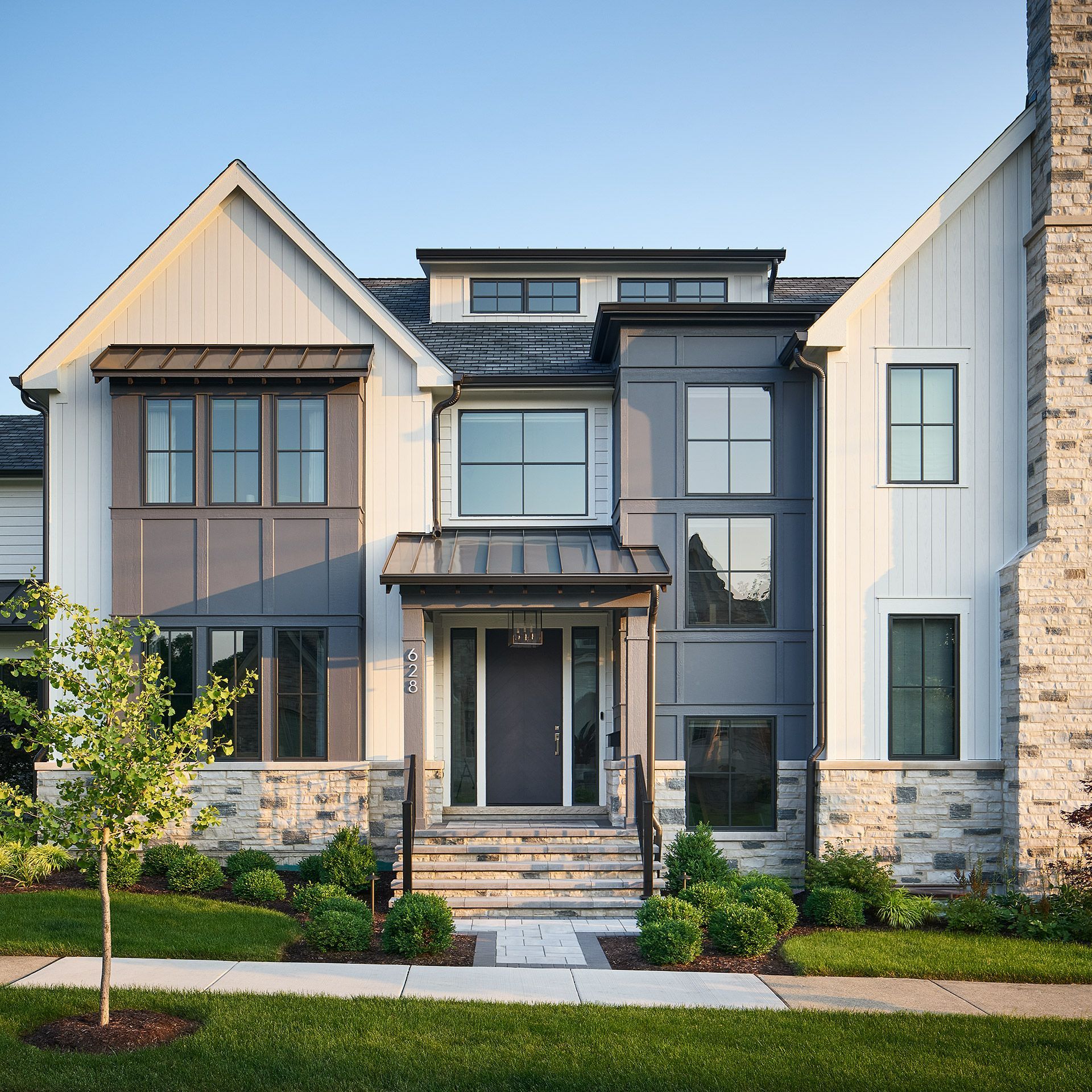 Modern two-story house exterior with stone accents, large windows, and a front walkway