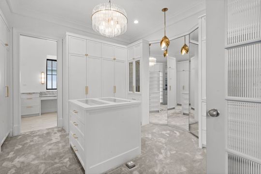 Bright white luxury bathroom with double vanity, freestanding tub, and chandelier lighting
