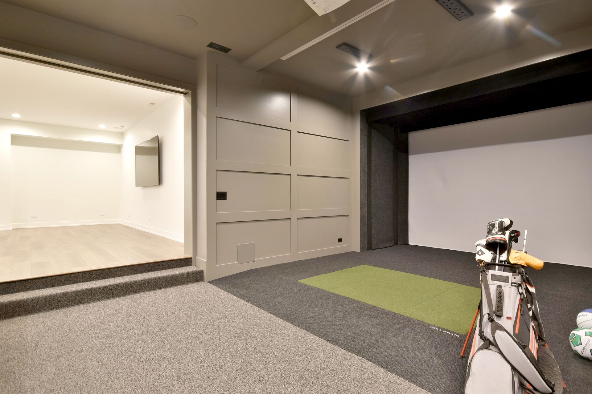 Modern room with carpet, built-in cabinets, and a small practice area with a golf bag on the right