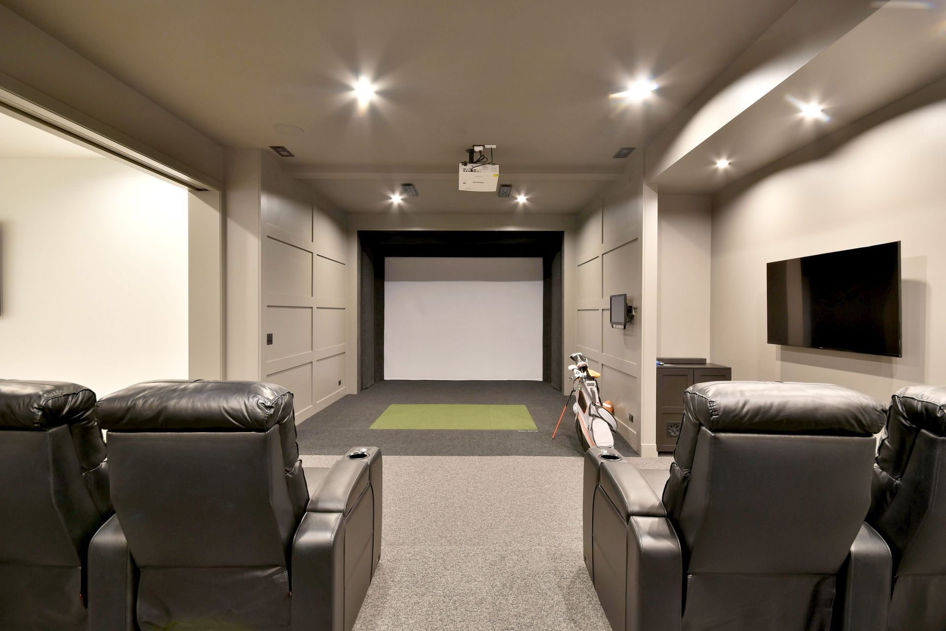 Modern home theater room with two leather recliners, recessed ceiling lights, and a large projection screen.