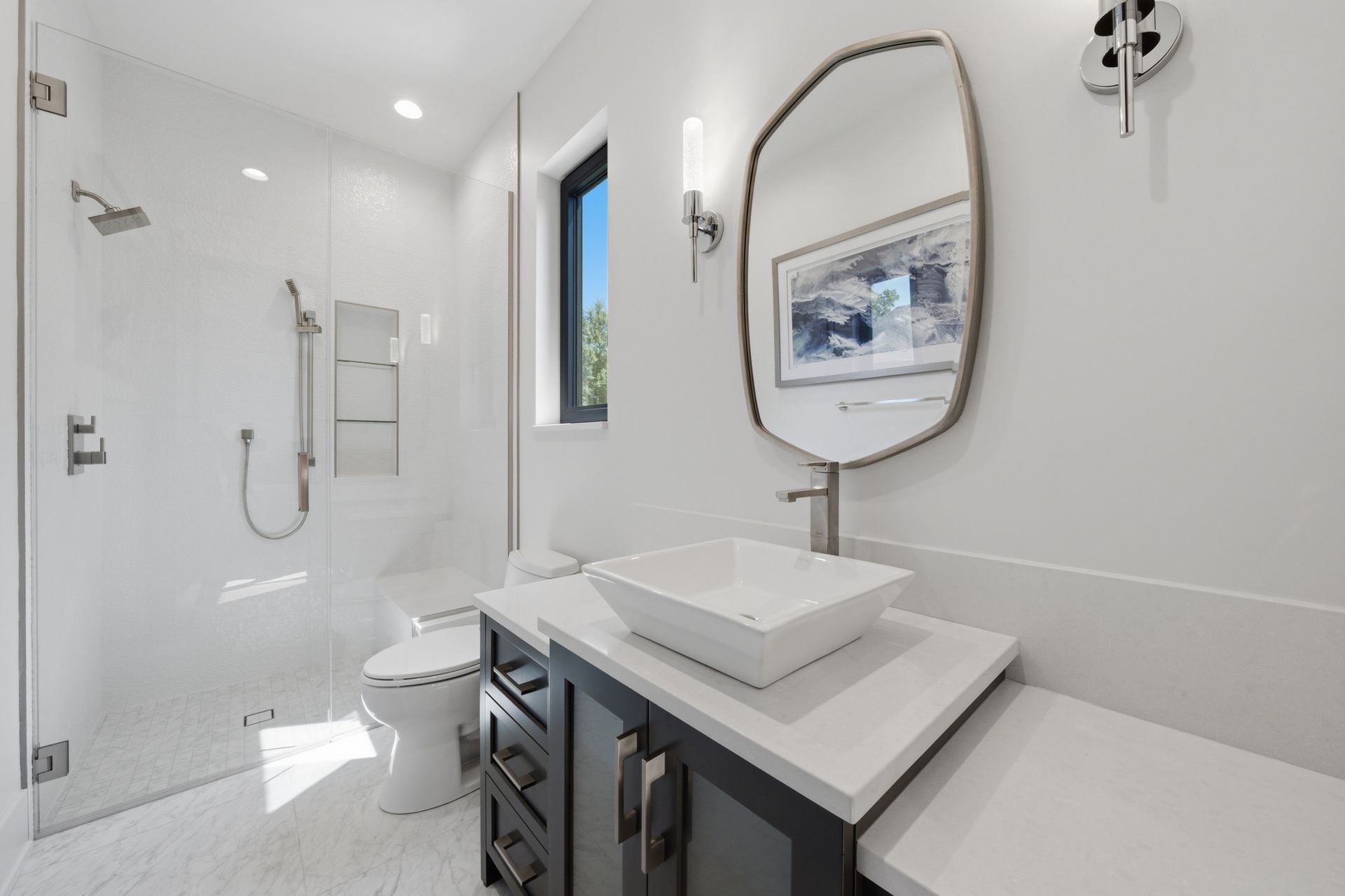 Bright modern bathroom with walk-in shower, toilet, sink vanity, and large mirror