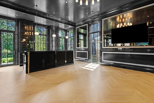 Modern lounge with black cabinetry, large windows, wood floor, and a wall-mounted TV