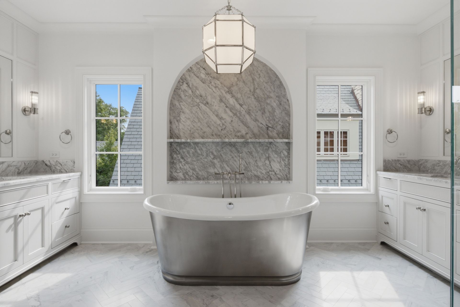 Luxury white bathroom with freestanding tub, marble shower alcove, and large windows.