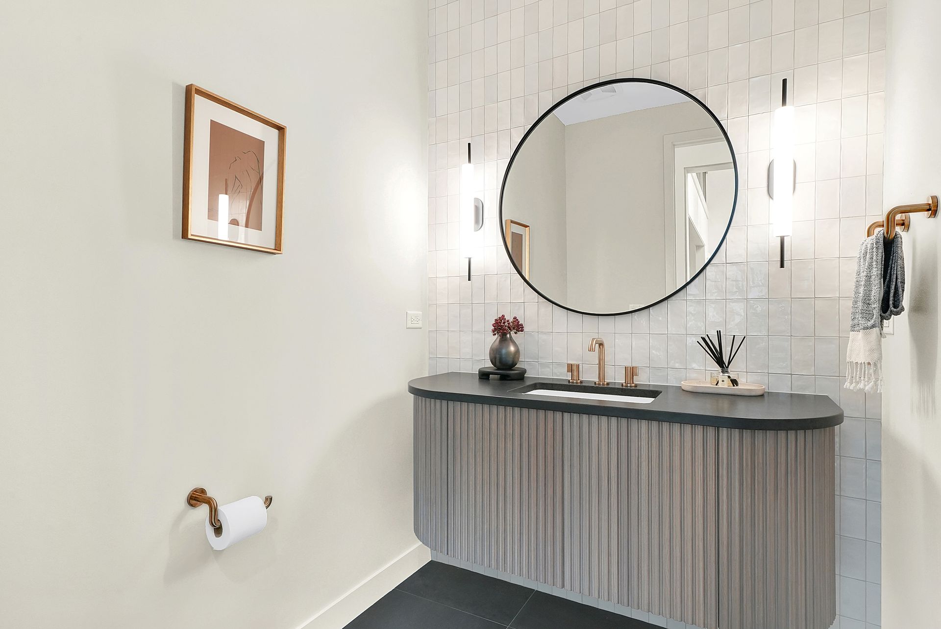 Minimalist bathroom vanity with round mirror, wall sconce lights, and striped cabinet