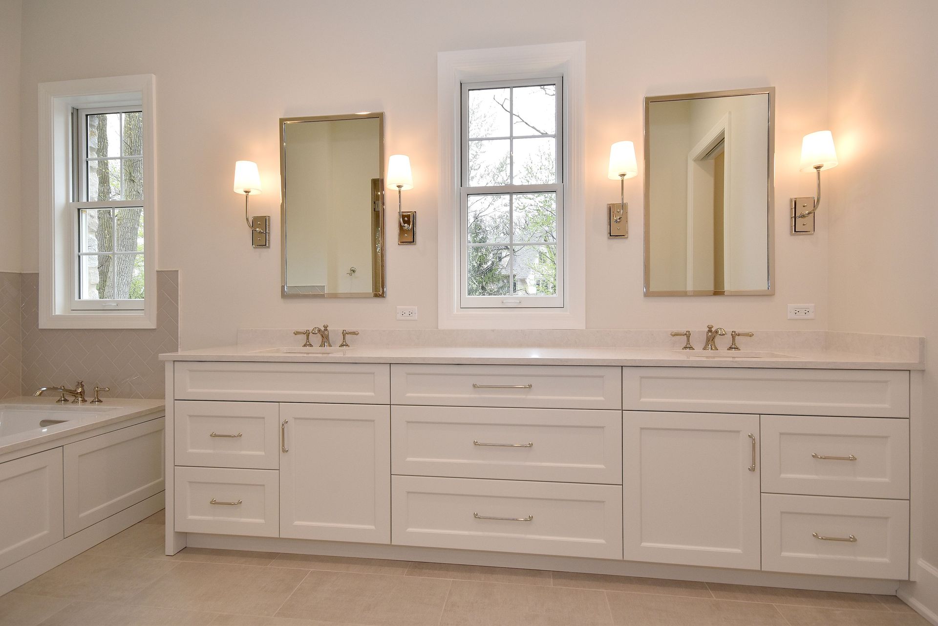Bright white bathroom with double vanity, wall mirrors, sconces, and a window