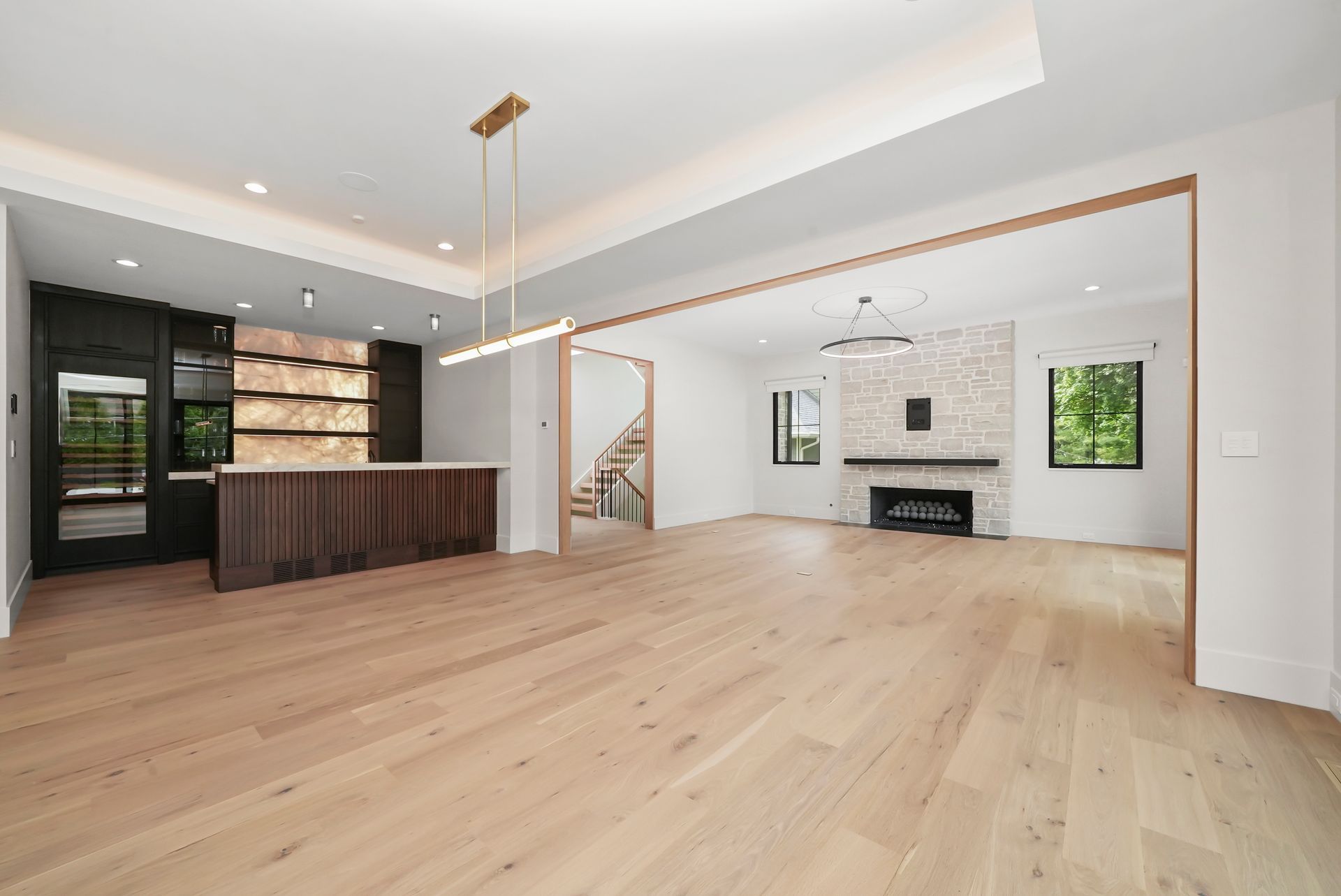Empty modern open-plan living room with light wood floors, white walls, and a kitchen island