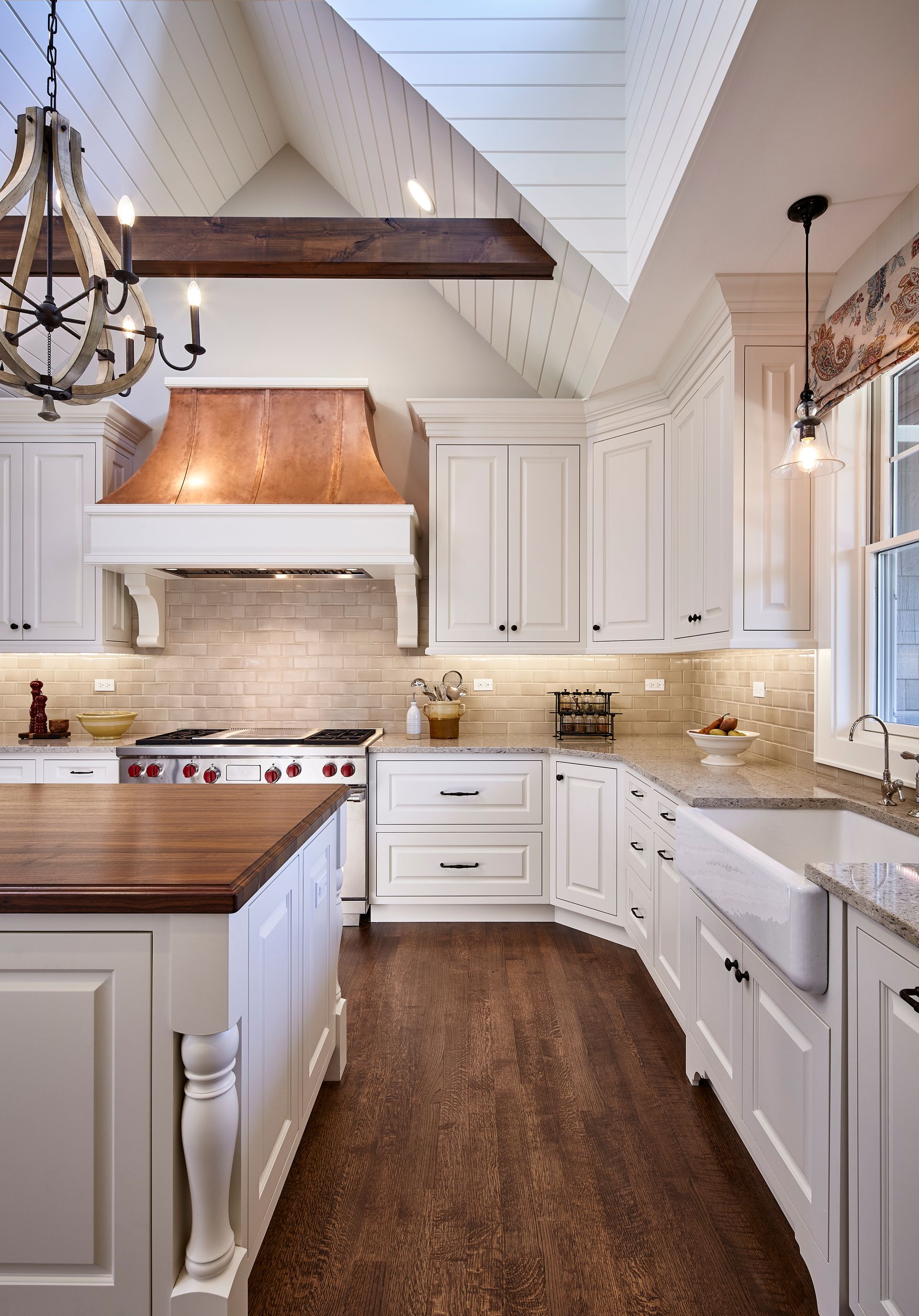 Bright white kitchen with wood countertops, copper range hood, and a long narrow island.