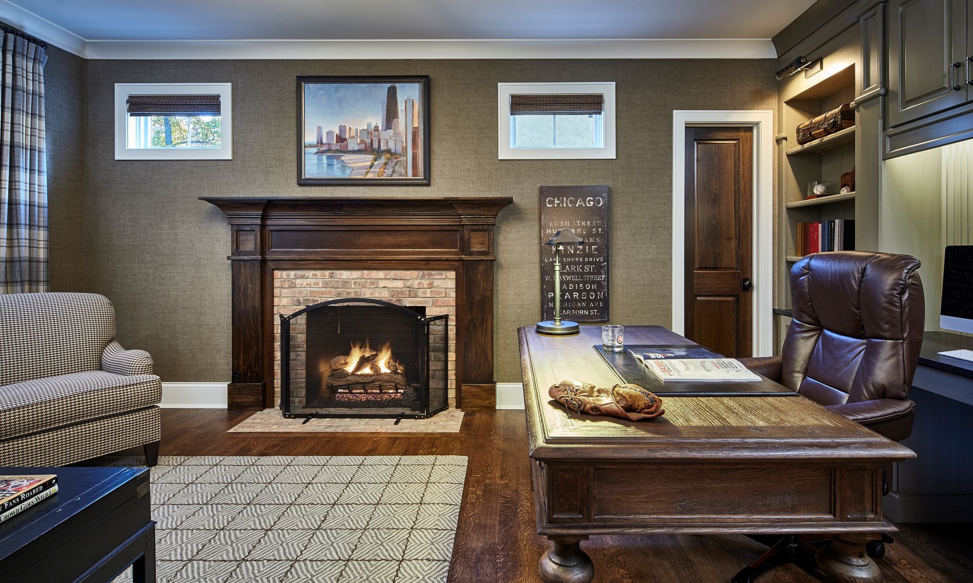 Cozy office with stone fireplace, wooden desk, leather chair, and wall art on beige walls