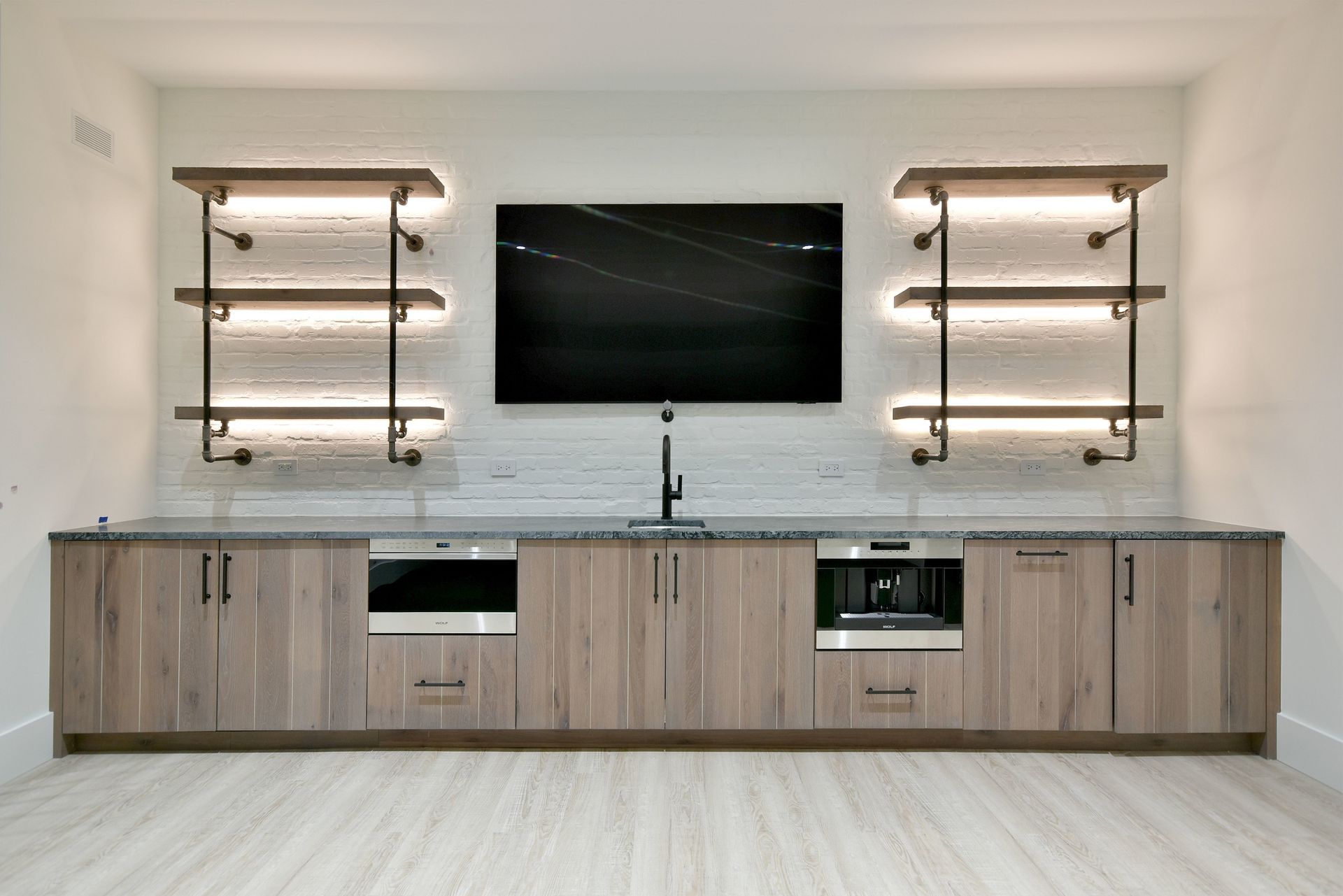 Modern built-in entertainment wall with TV, shelves, and long wood cabinet in a bright room