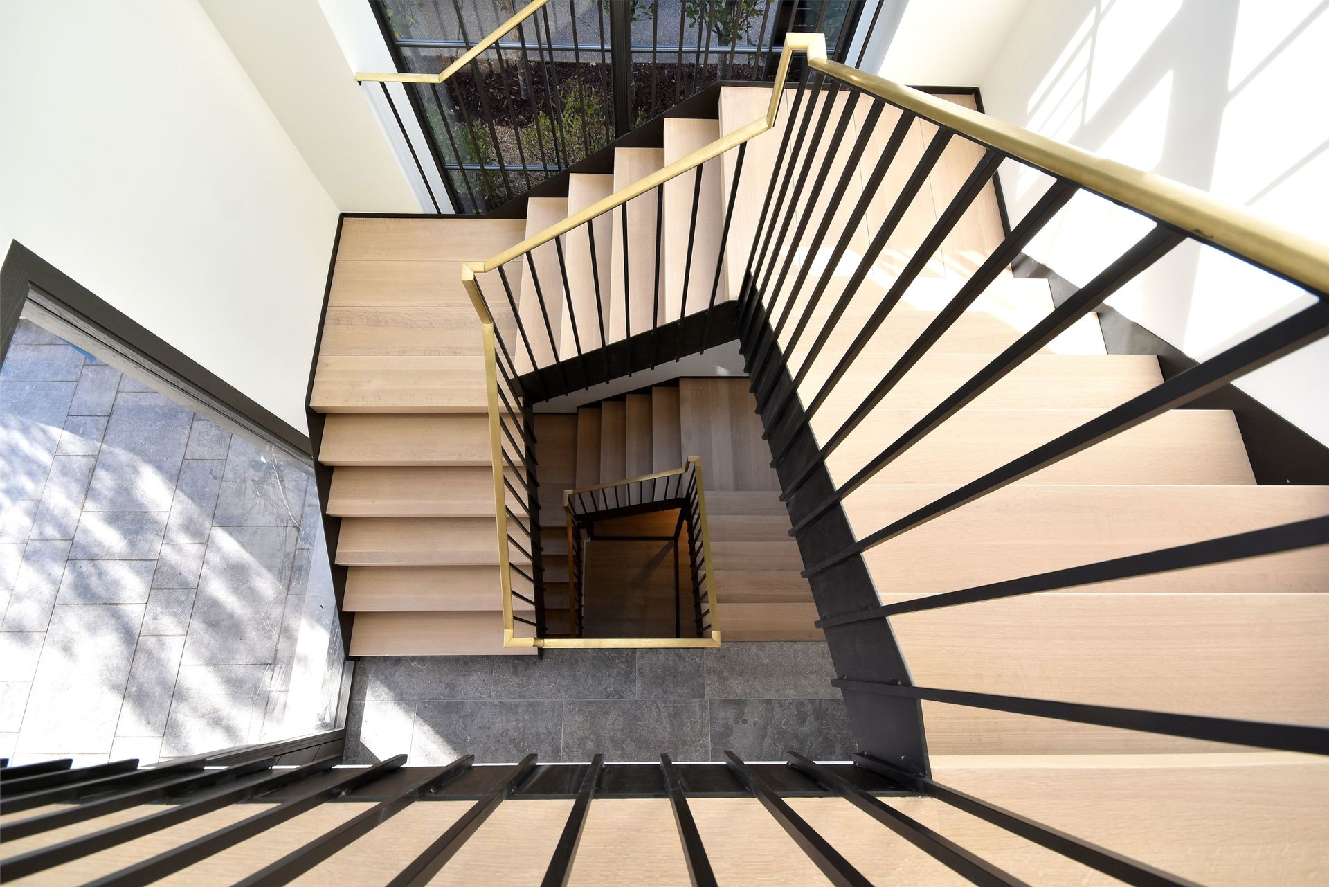 Top-down view of a spiral staircase with black railings and beige steps around a central opening