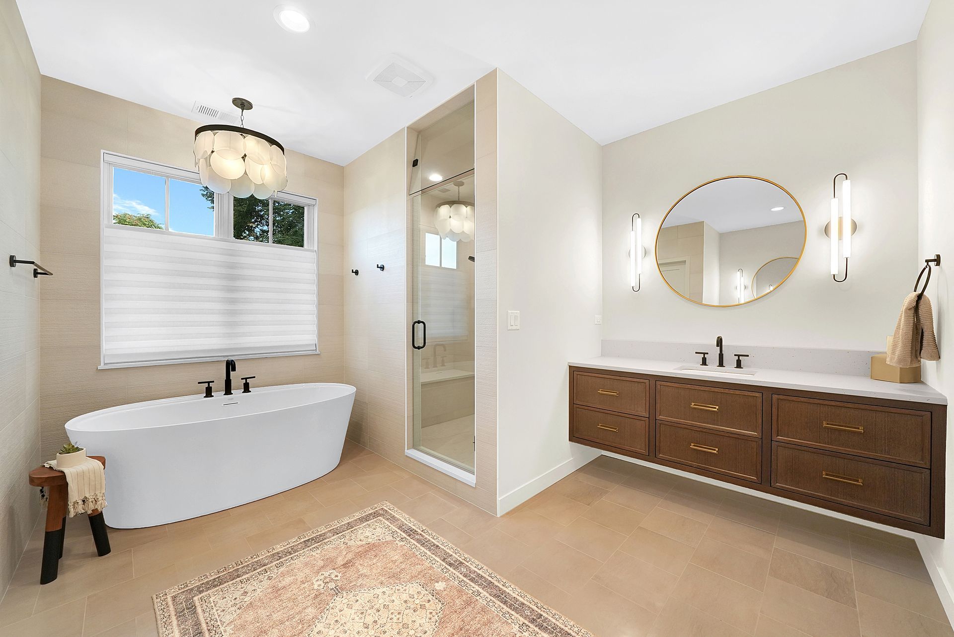 Bright modern bathroom with freestanding tub, glass shower, double vanity, and round mirror
