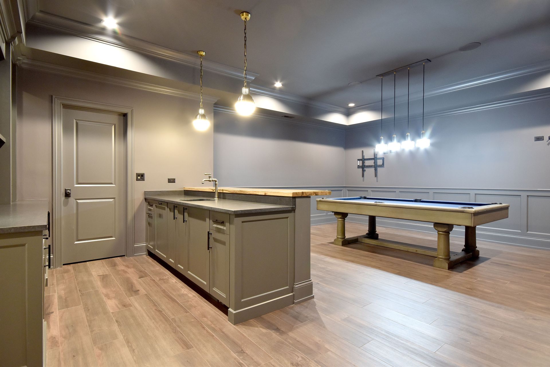 Spacious basement with pool table, kitchen island, gray walls, and wood floors