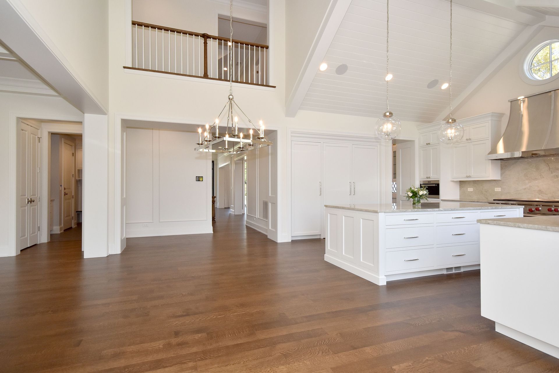 Bright open-concept kitchen and living area with hardwood floors, white cabinets, and a chandelier.