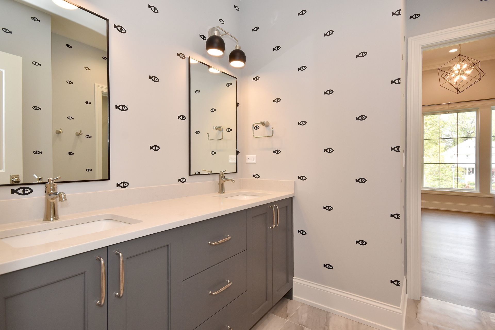 Modern bathroom with double vanity, gray cabinets, white countertop, and patterned wallpaper