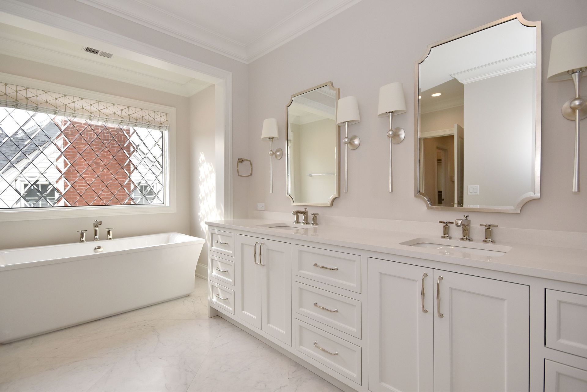 Bright luxury bathroom with freestanding tub, double vanity, and large mirrors by a window
