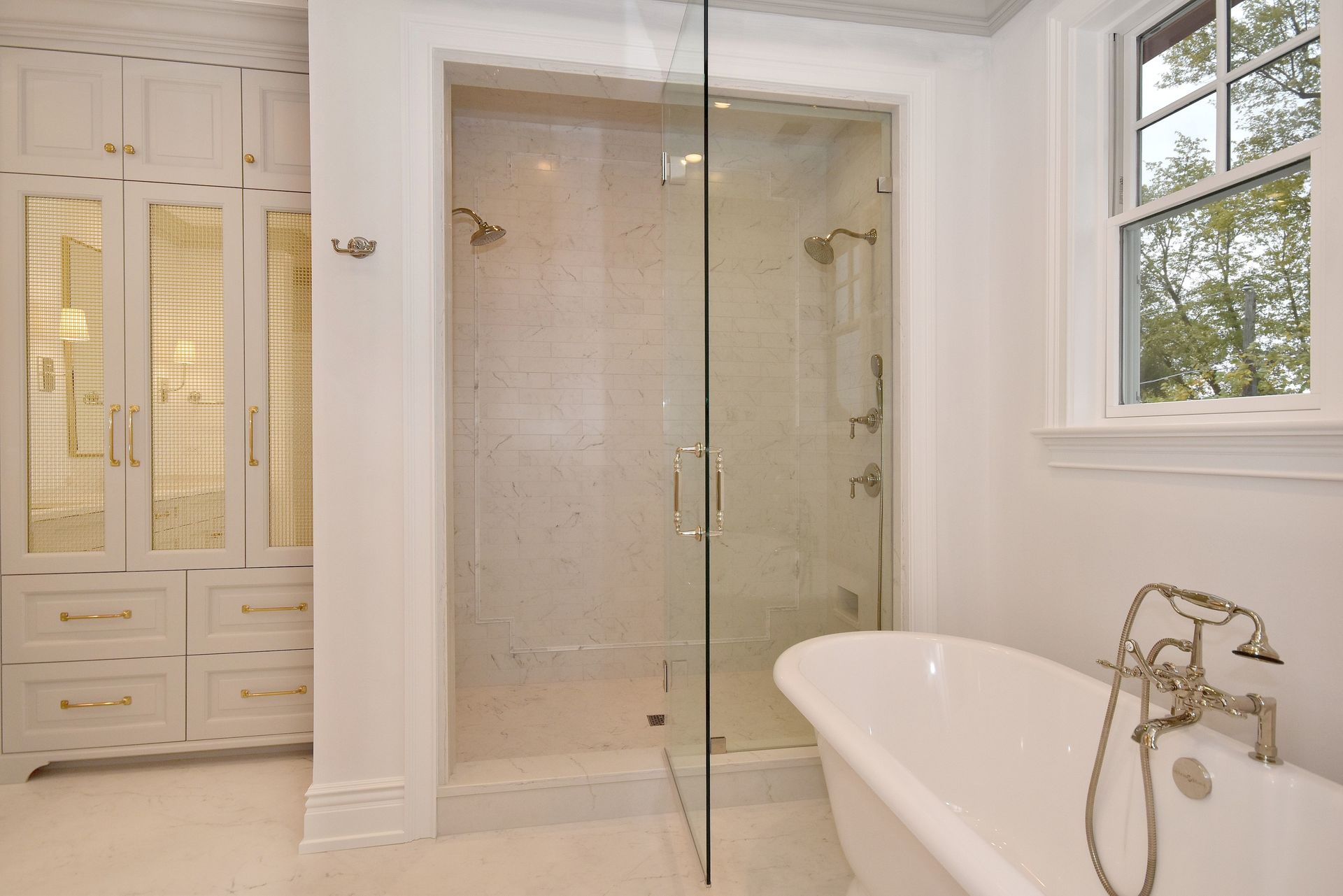 Bright bathroom with glass shower, soaking tub, and white built-in cabinets