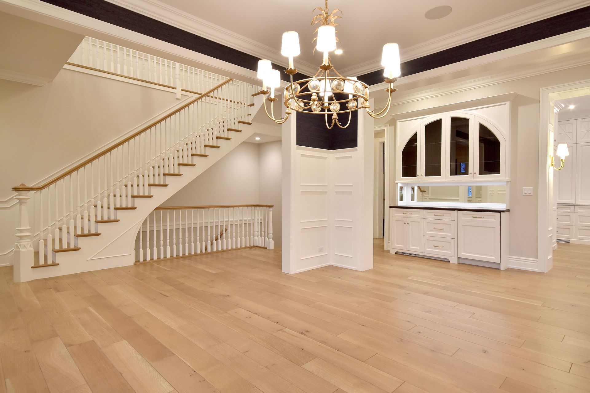 Elegant empty foyer with a staircase, chandelier, hardwood floors, and built-in cabinets