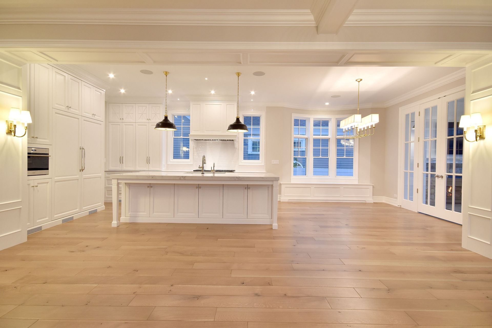 Bright white modern kitchen with large island, hardwood floors, and lots of windows.