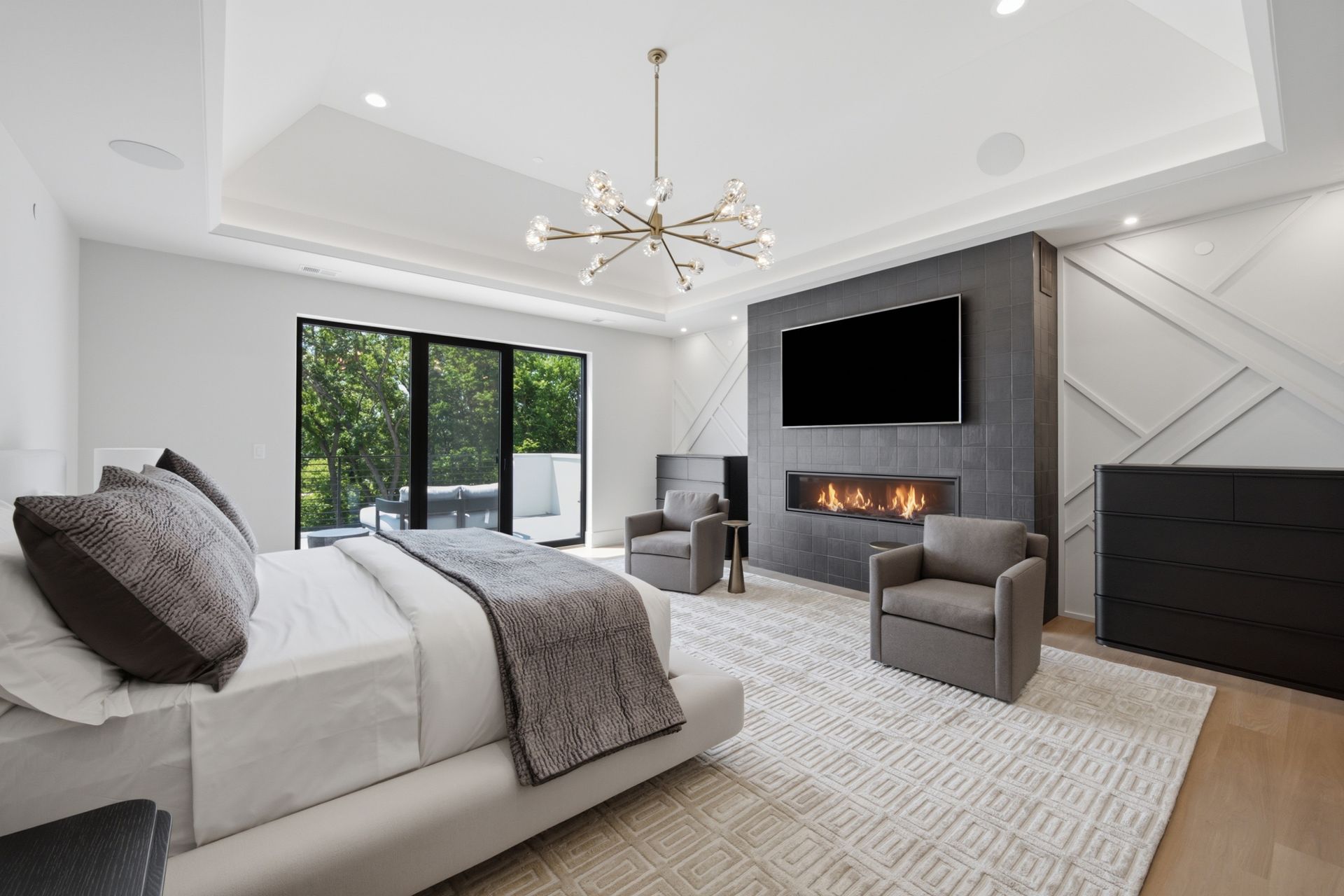 Modern gray living room with fireplace, wall-mounted TV, sectional sofa, and sliding glass doors to the patio
