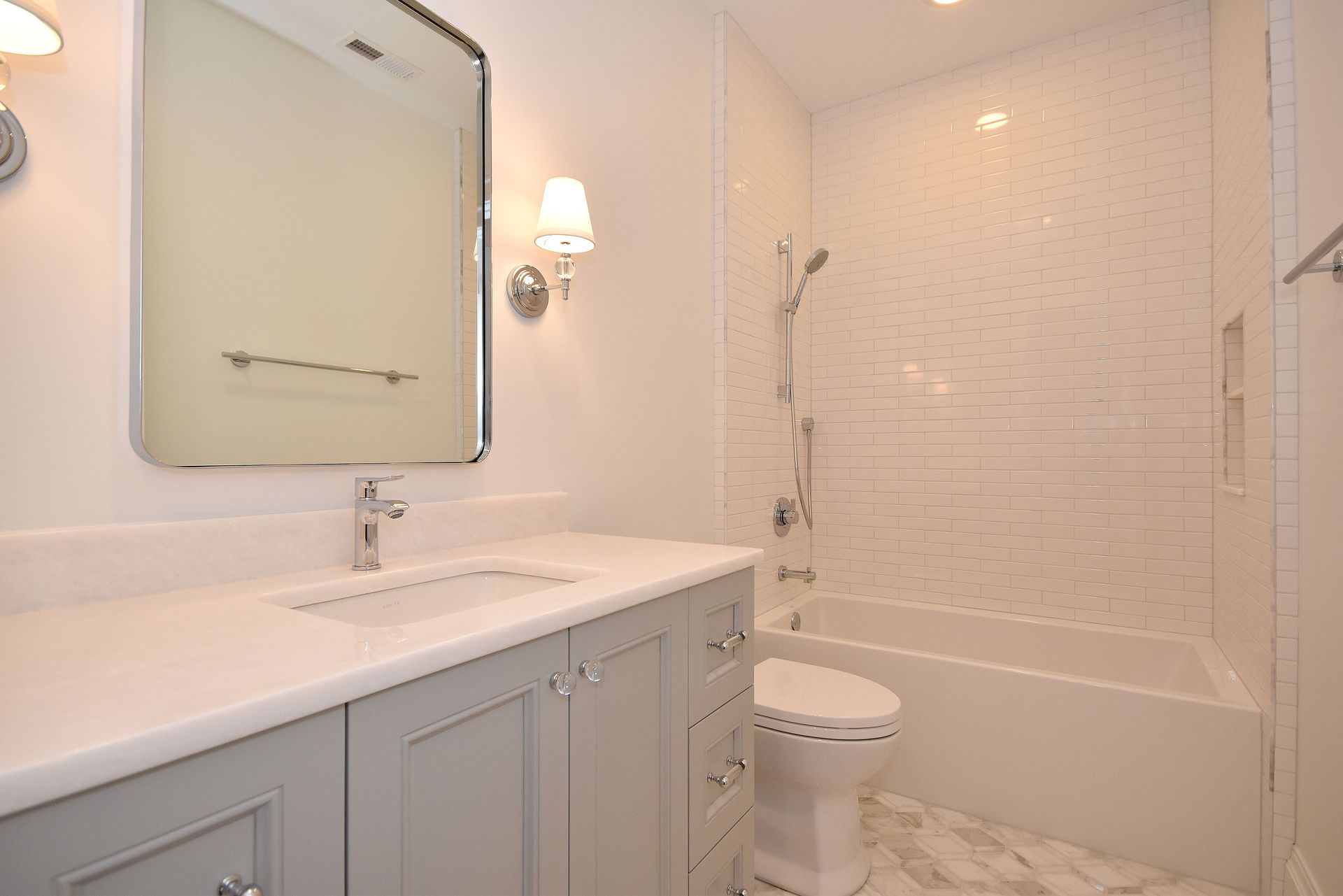 Bright white bathroom with vanity sink, mirror, toilet, and tiled shower area