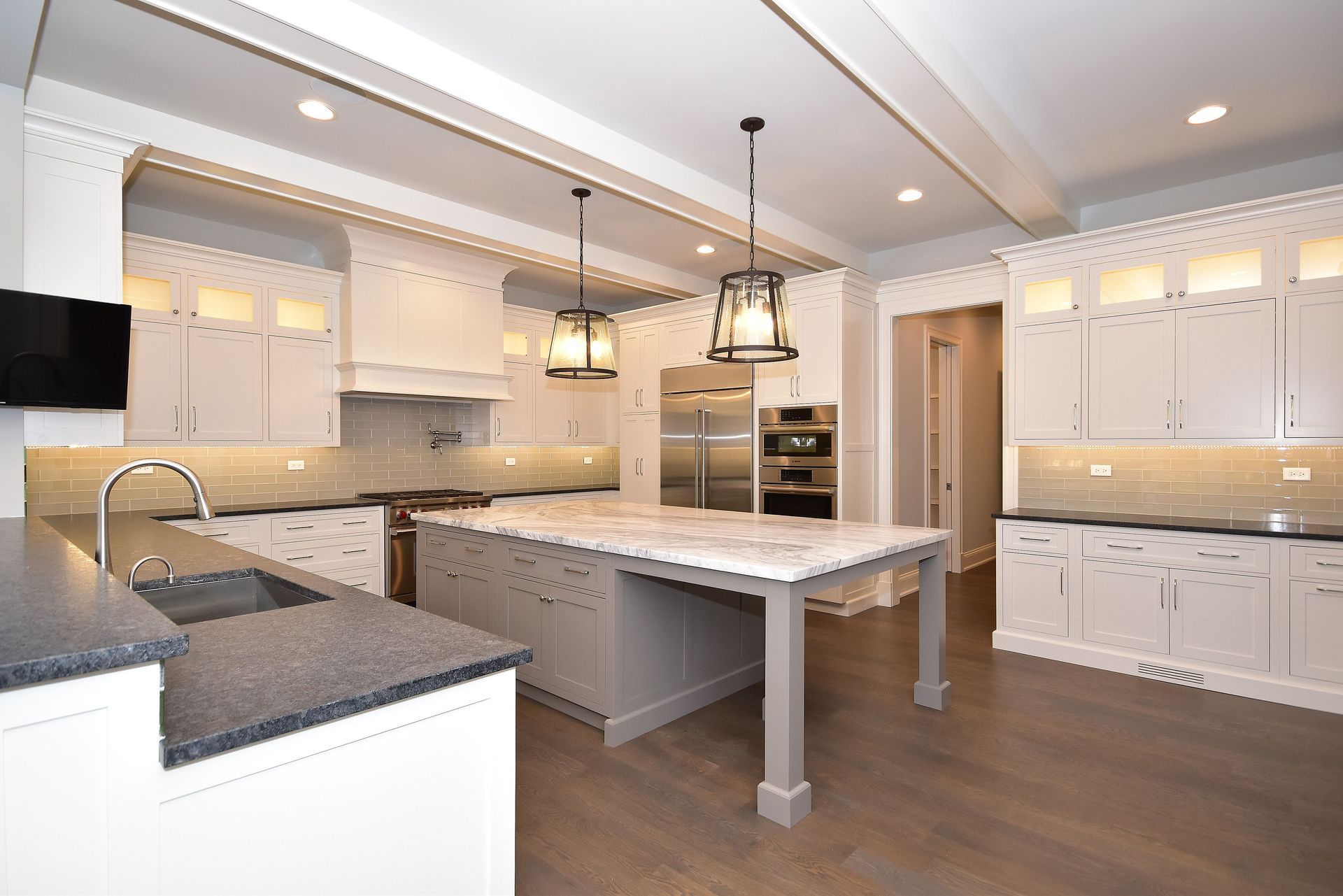 Bright modern kitchen with white cabinets, gray countertops, and a central island with pendant lights.