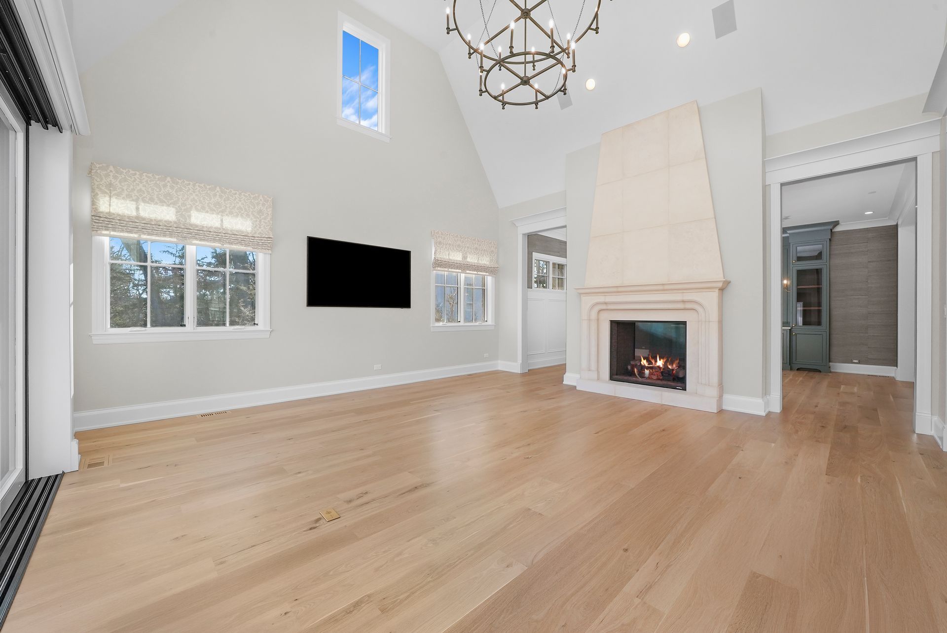 Bright modern living room with vaulted ceilings, fireplace, TV, and light wood floors