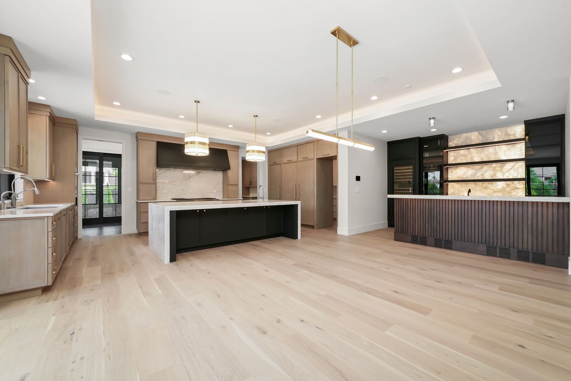Modern open-concept kitchen and living area with light wood floors, white island, and dark wood cabinets