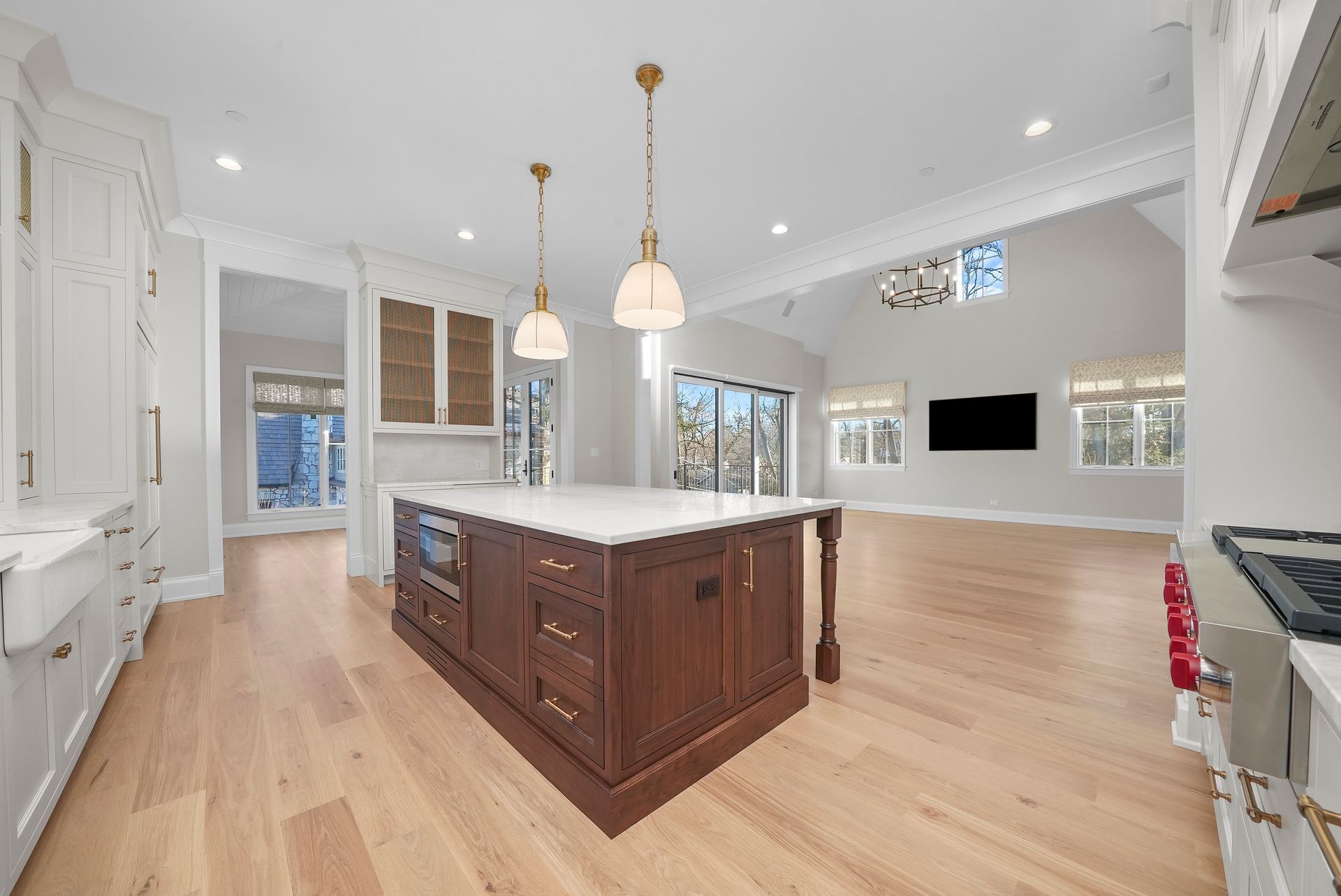 Bright modern kitchen with white cabinets, a large island, pendant lights, and hardwood floors