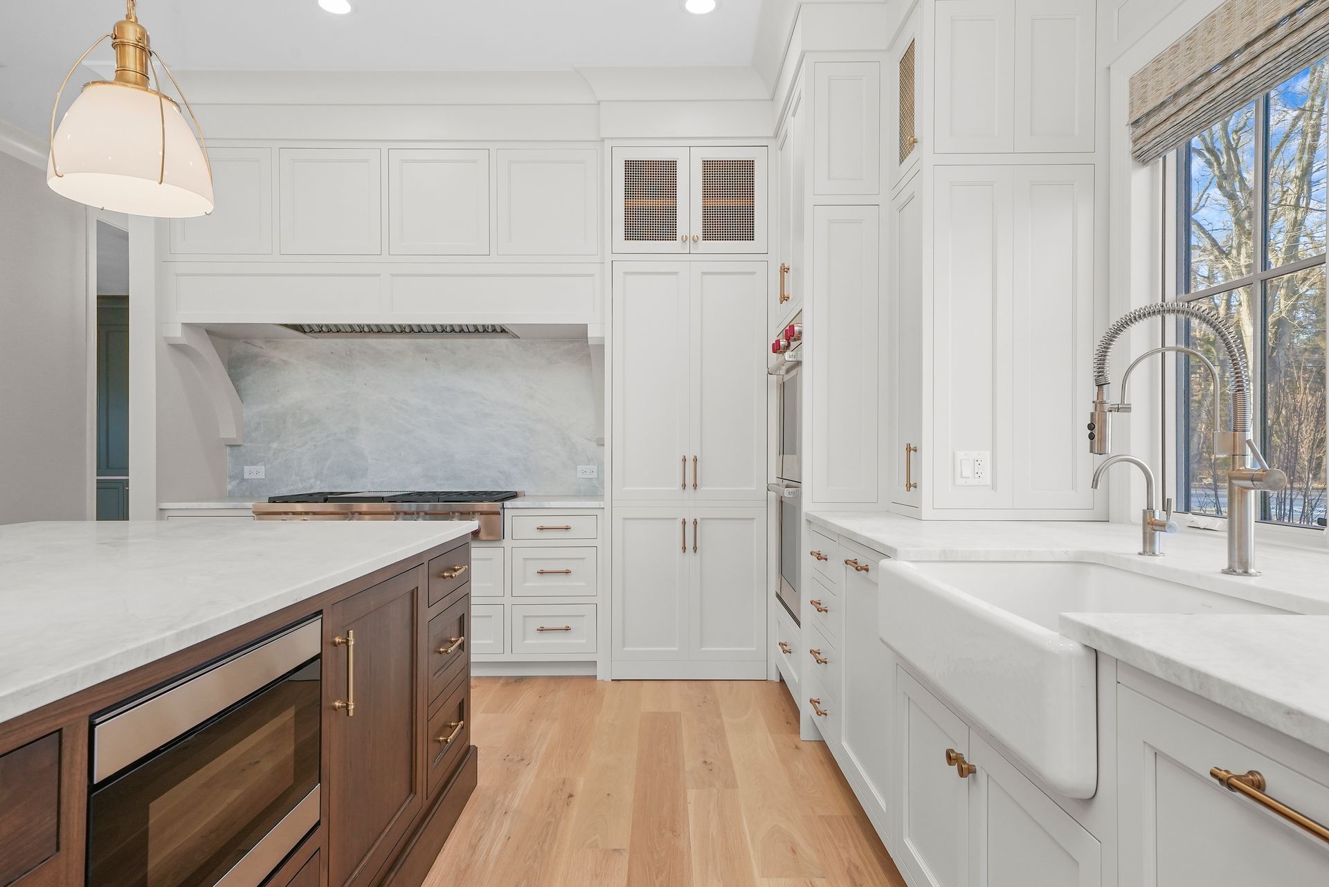 Bright white kitchen with wood floors, large sink, island, and marble backsplash