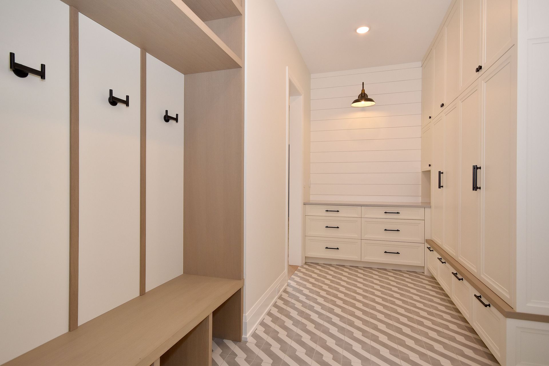 Bright walk-in closet with white built-in cabinets, wood benches, and patterned carpet flooring.