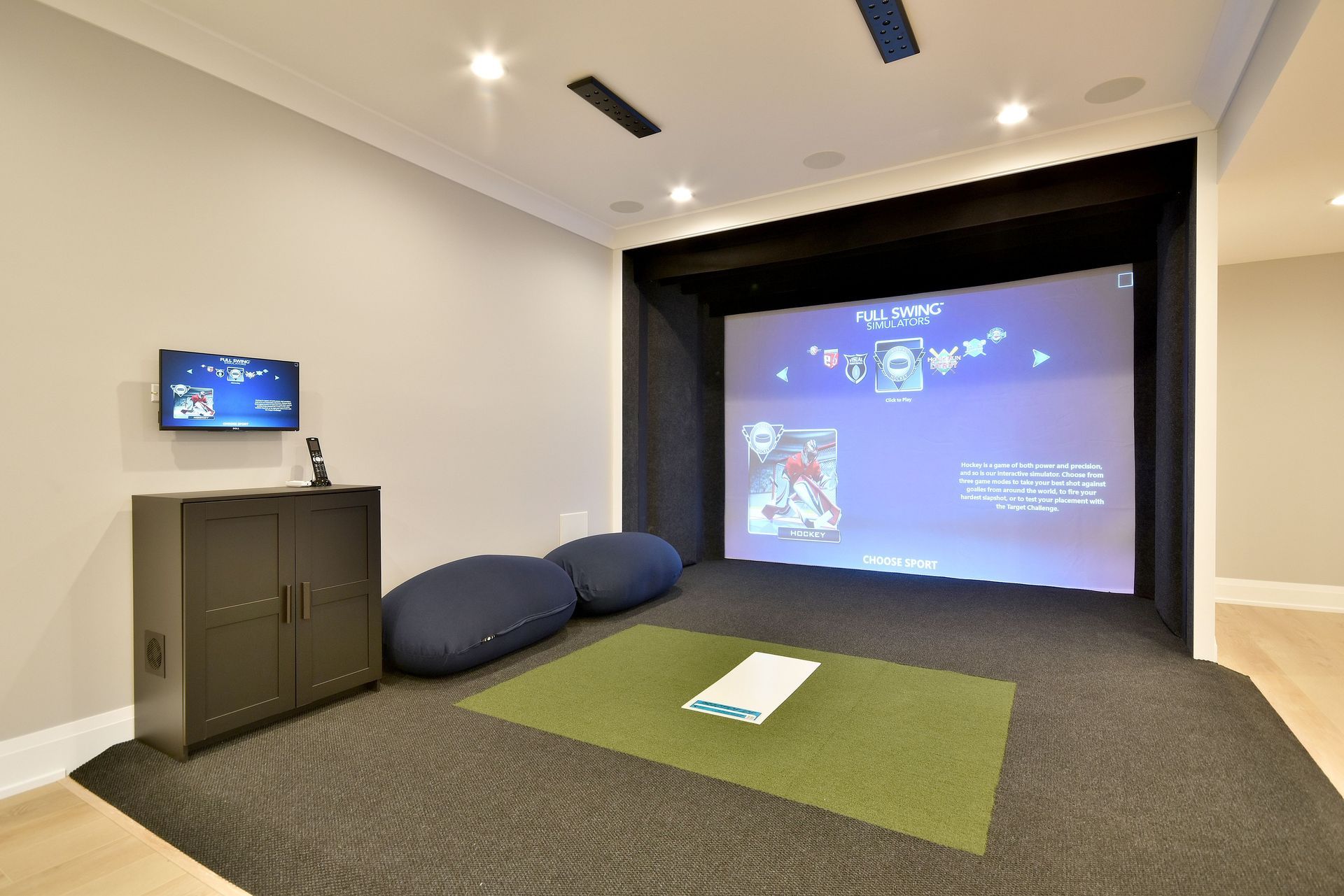 Home theater room with projector screen, blue beanbags, and green carpet area