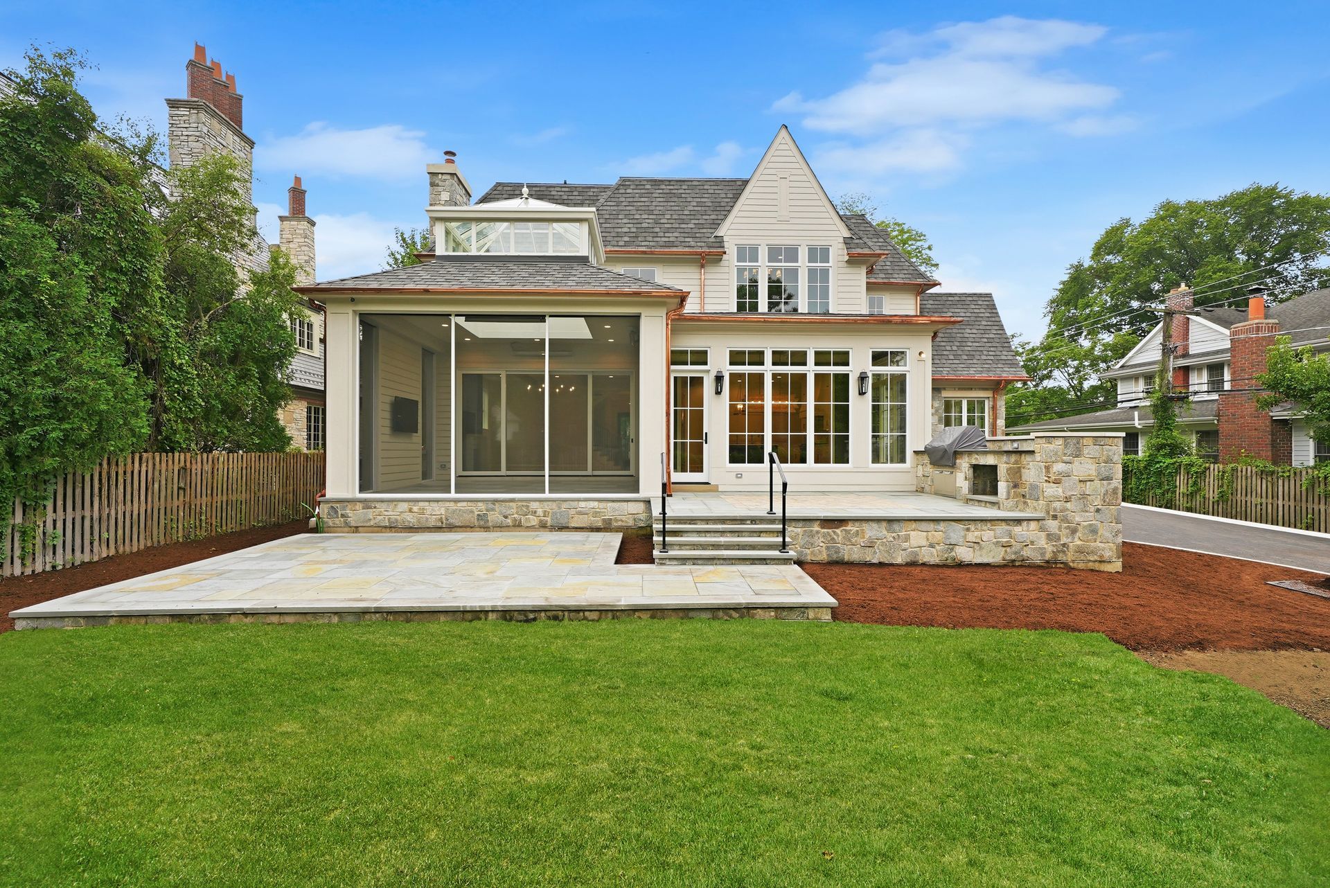 Modern two-story house with a large glass patio door, stone patio, and green lawn