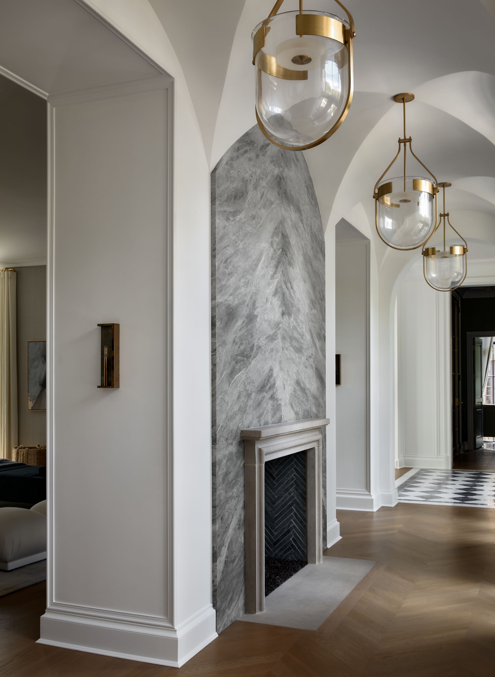 Elegant hallway with marble fireplace, brass pendant lights, and arched doorways
