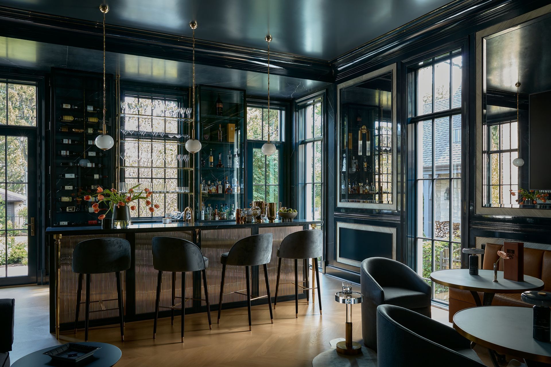 Stylish dark bar interior with high stools, tables, and large windows, lit by warm ambient light