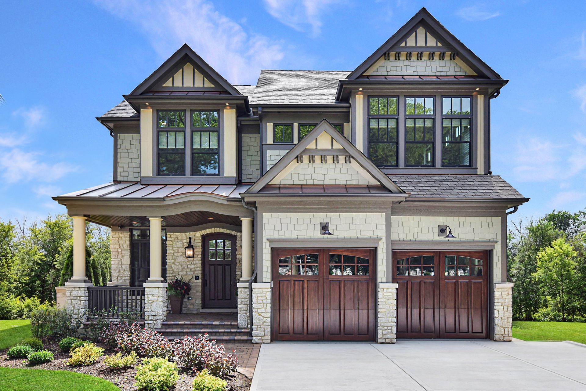 Two-story Craftsman house with front porch, dark trim, and a double garage