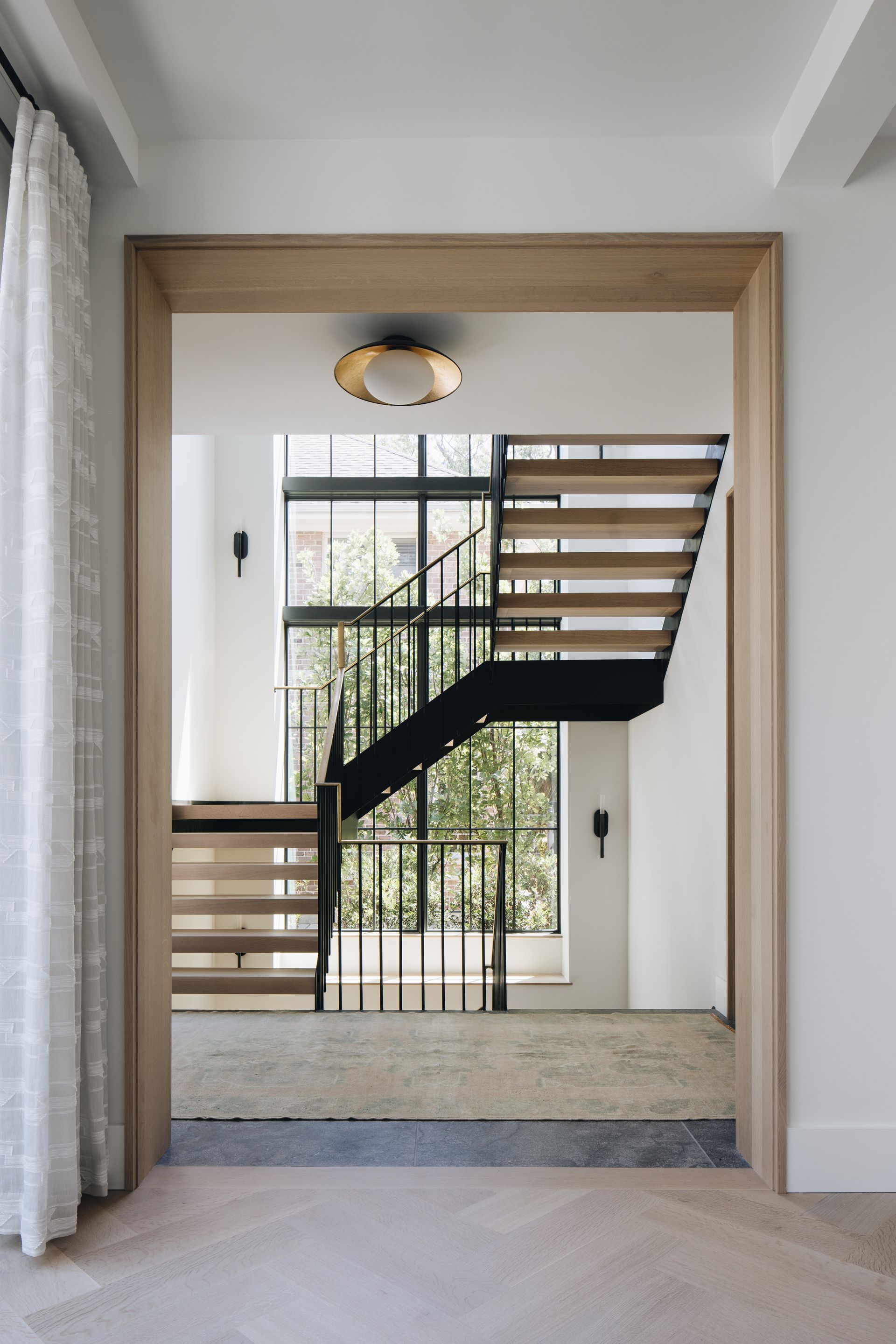 Modern staircase with wood treads and black stringer in a bright white interior hall